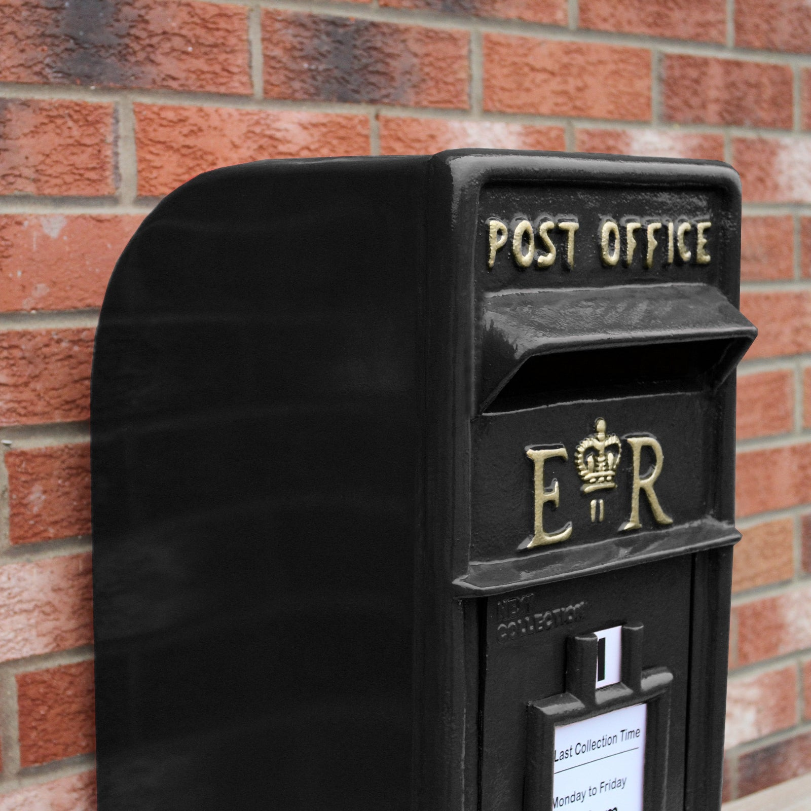 Buzón negro de metal con texto "Post Office" y escudo real.