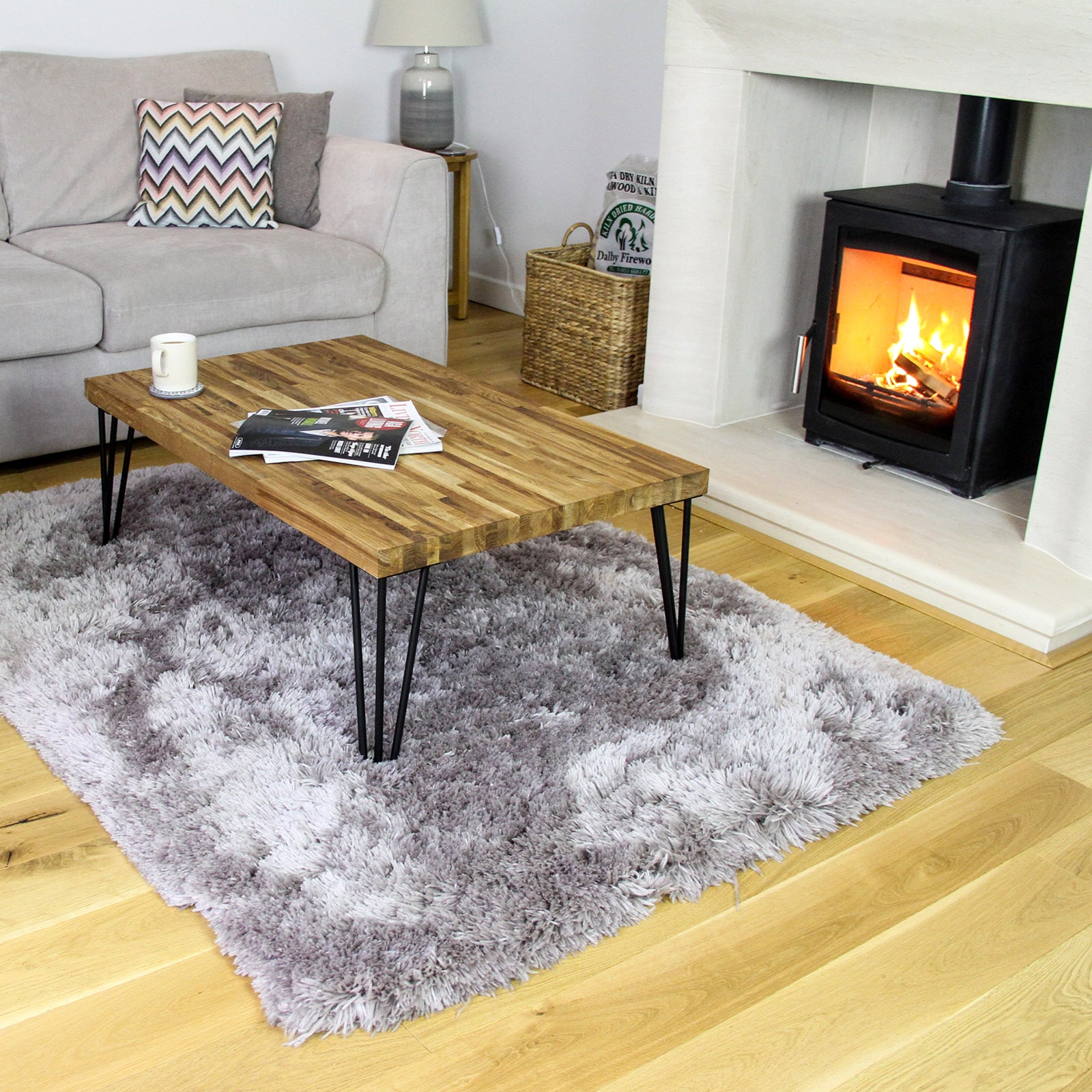 Una sala de estar con sofá, mesa de centro, alfombra y chimenea.