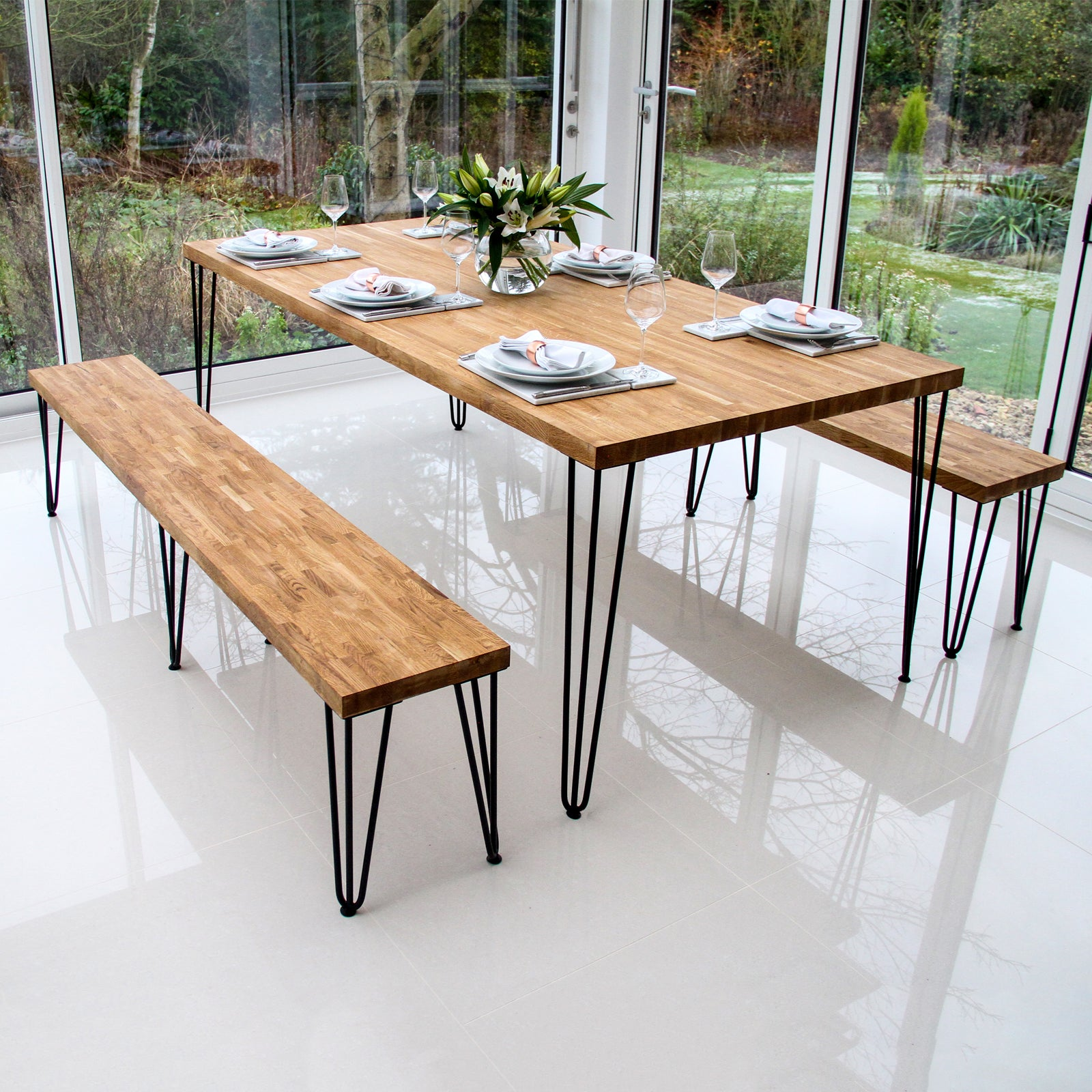 Mesa de comedor de madera con patas de horquilla y bancos, puesta para comer.