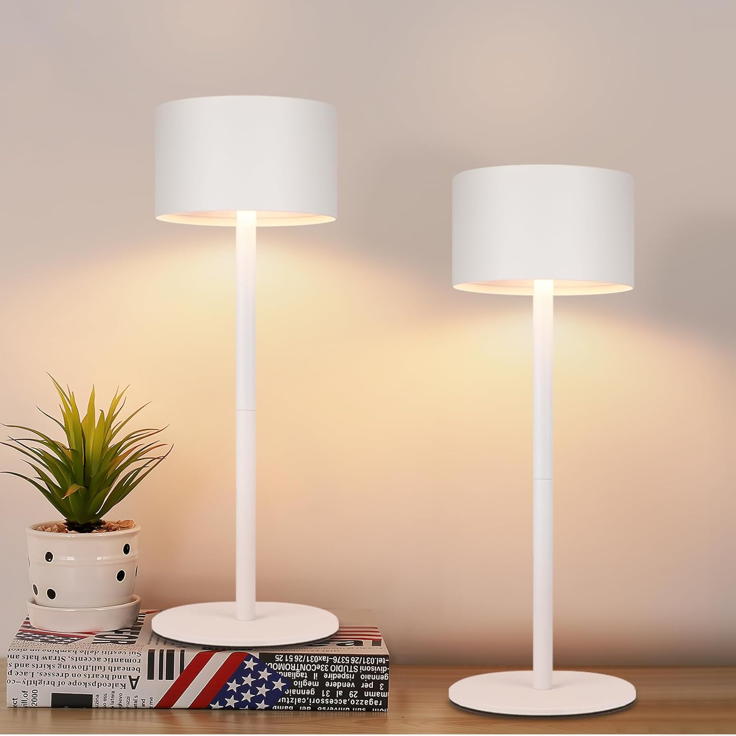 Dwie białe lampy stojące na stole obok rośliny doniczkowej.
