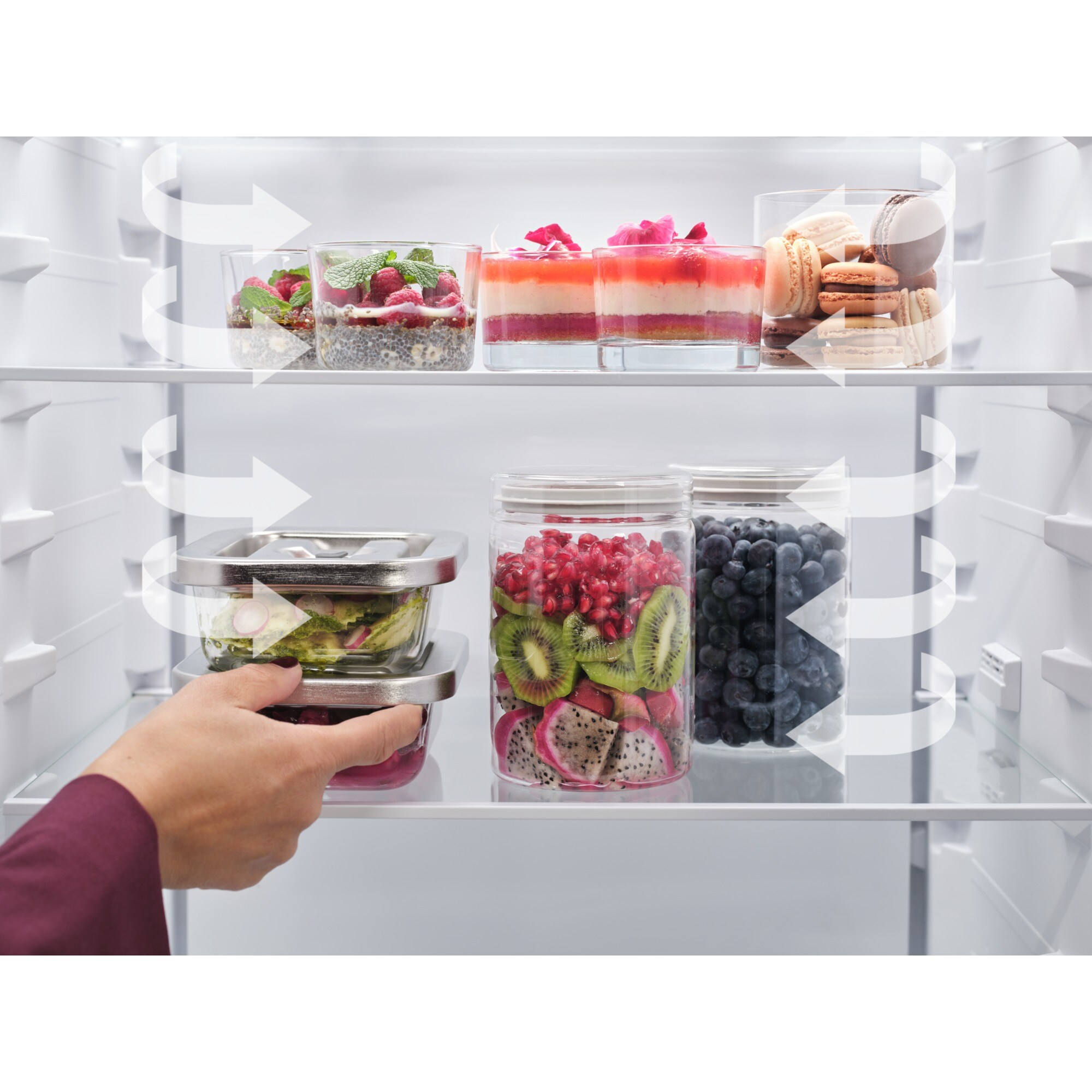 Vista interior de un refrigerador con frutas, postres y macarrones en estantes.