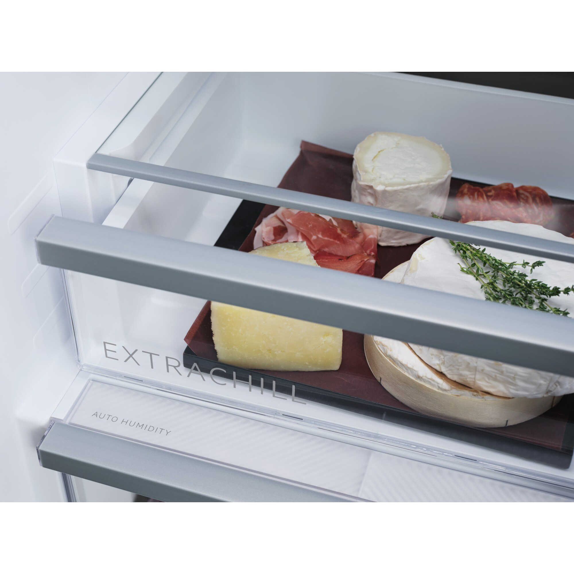 Un cajón de refrigerador con varios quesos y jamón.
