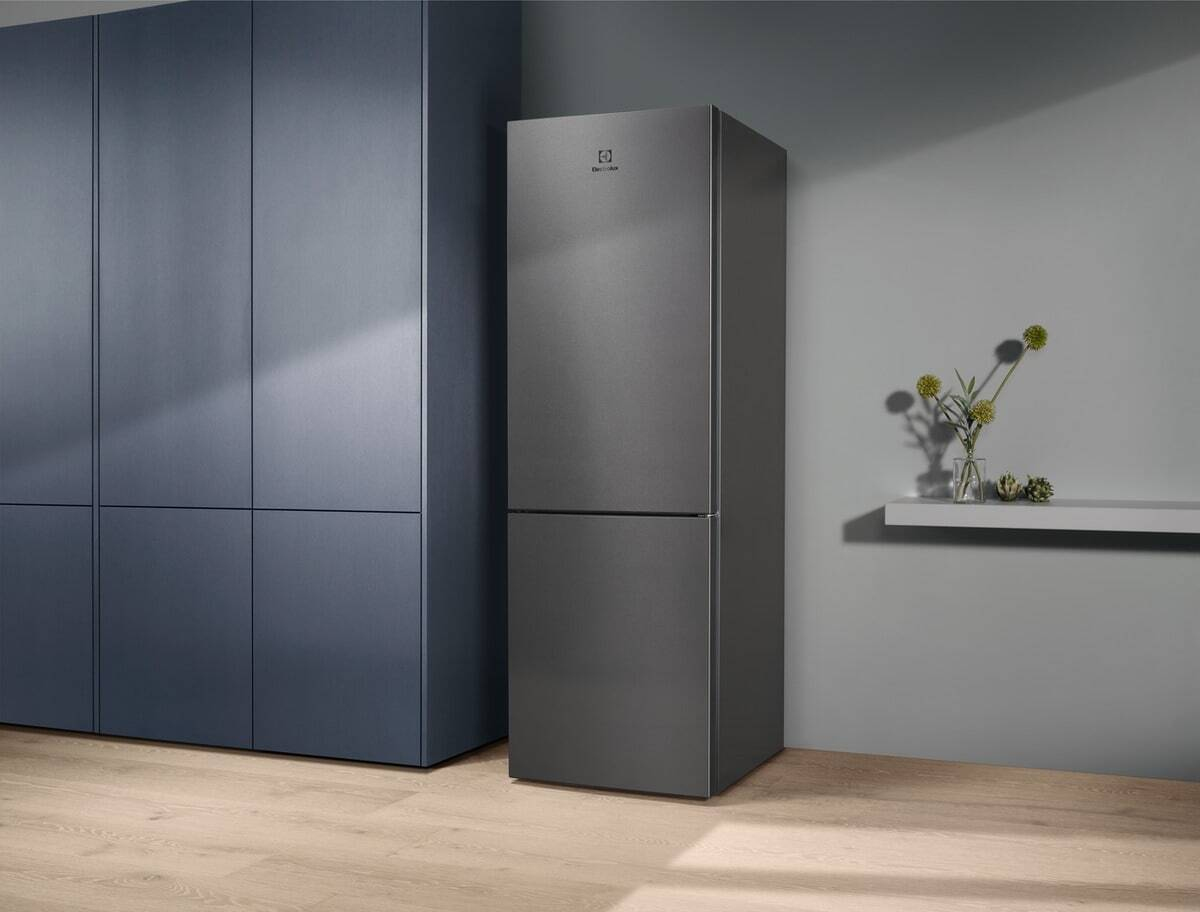 Un refrigerador gris junto a armarios azul oscuro sobre suelo de madera.