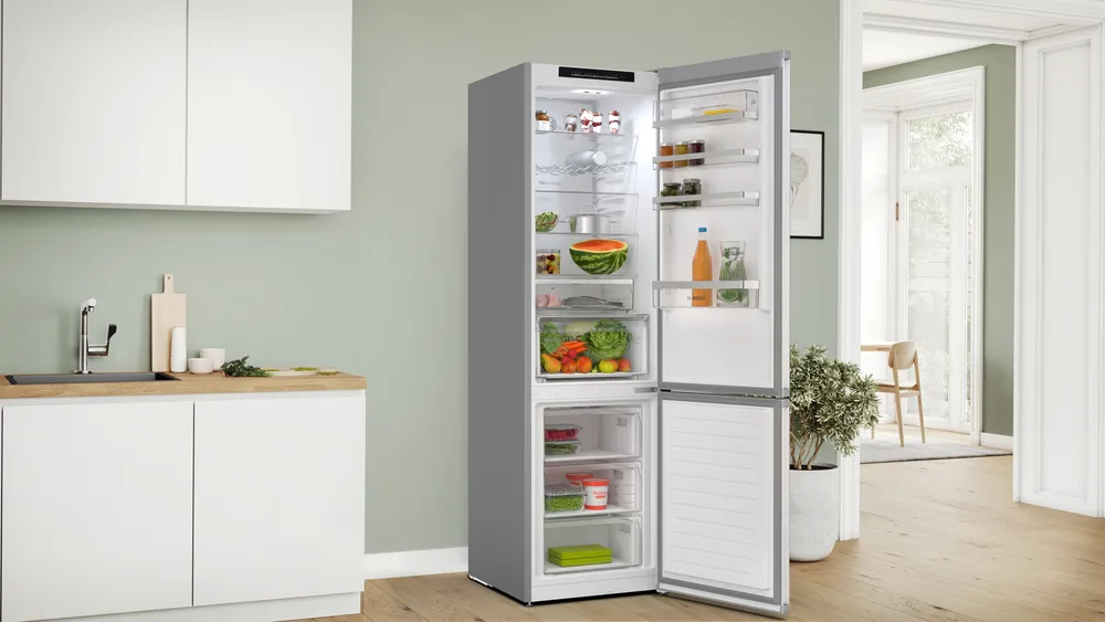 Offener Kühlschrank mit Lebensmitteln und Blick auf einen Essbereich.