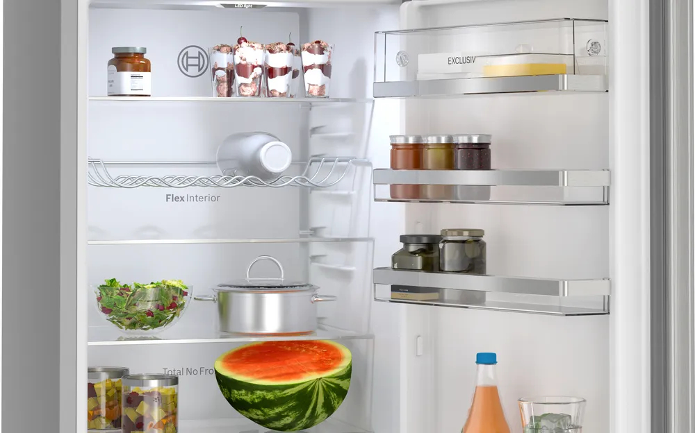 Ein offener Kühlschrank mit Gläsern, Marmelade, Salat, Topf, Wassermelone, Flasche.