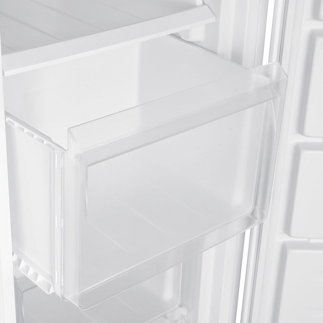 Un cajón de frigorífico blanco y vacío con asa transparente contra una pared acanalada.