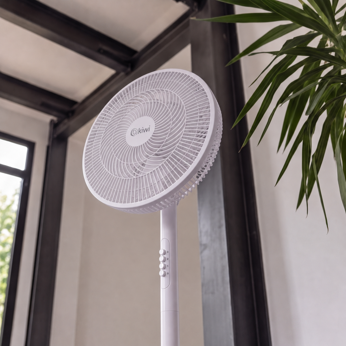 Un ventilatore da terra bianco è posizionato vicino a una pianta vicino a una finestra.