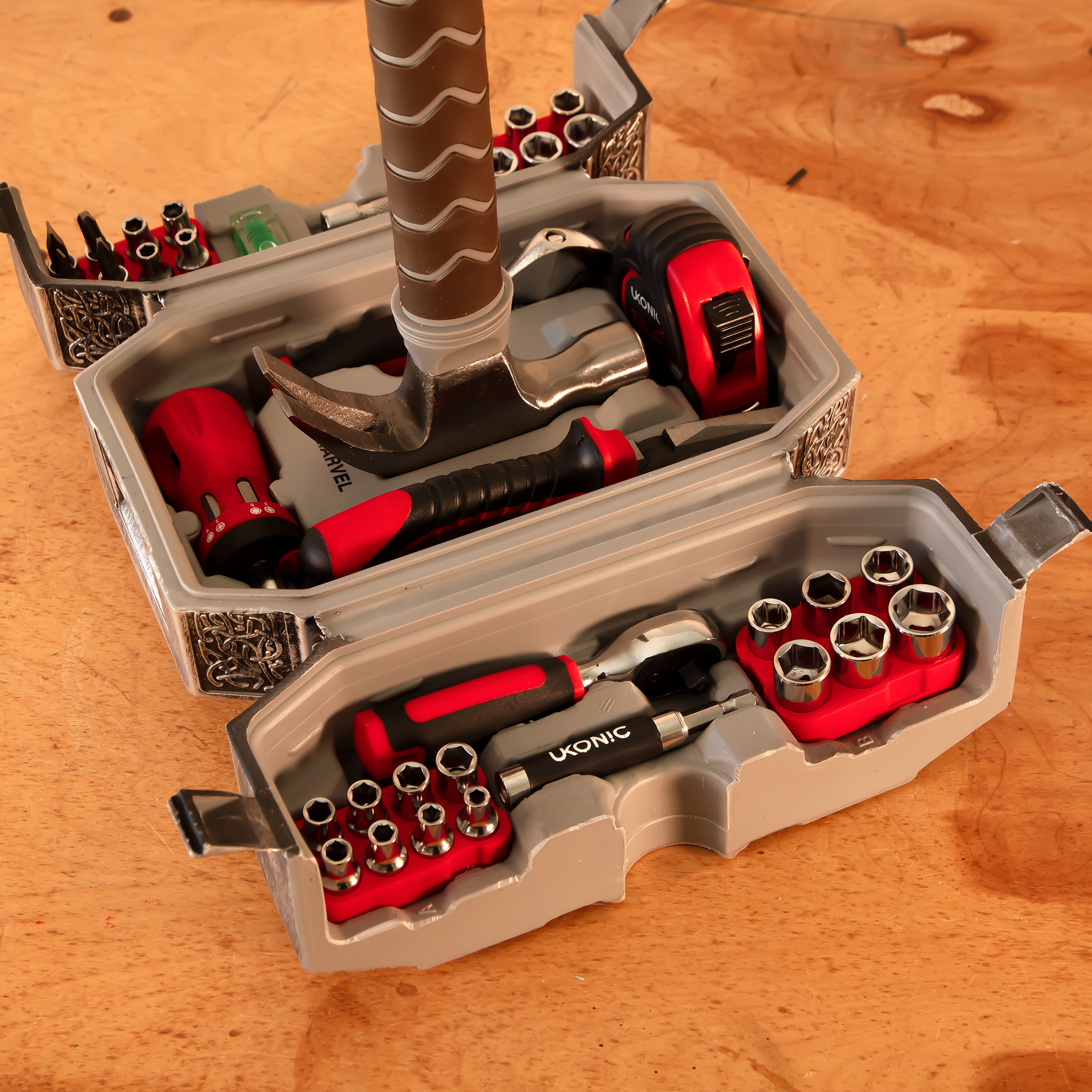 Una caja de herramientas gris con forma de martillo de Thor contiene varias herramientas, destornilladores y vasos.