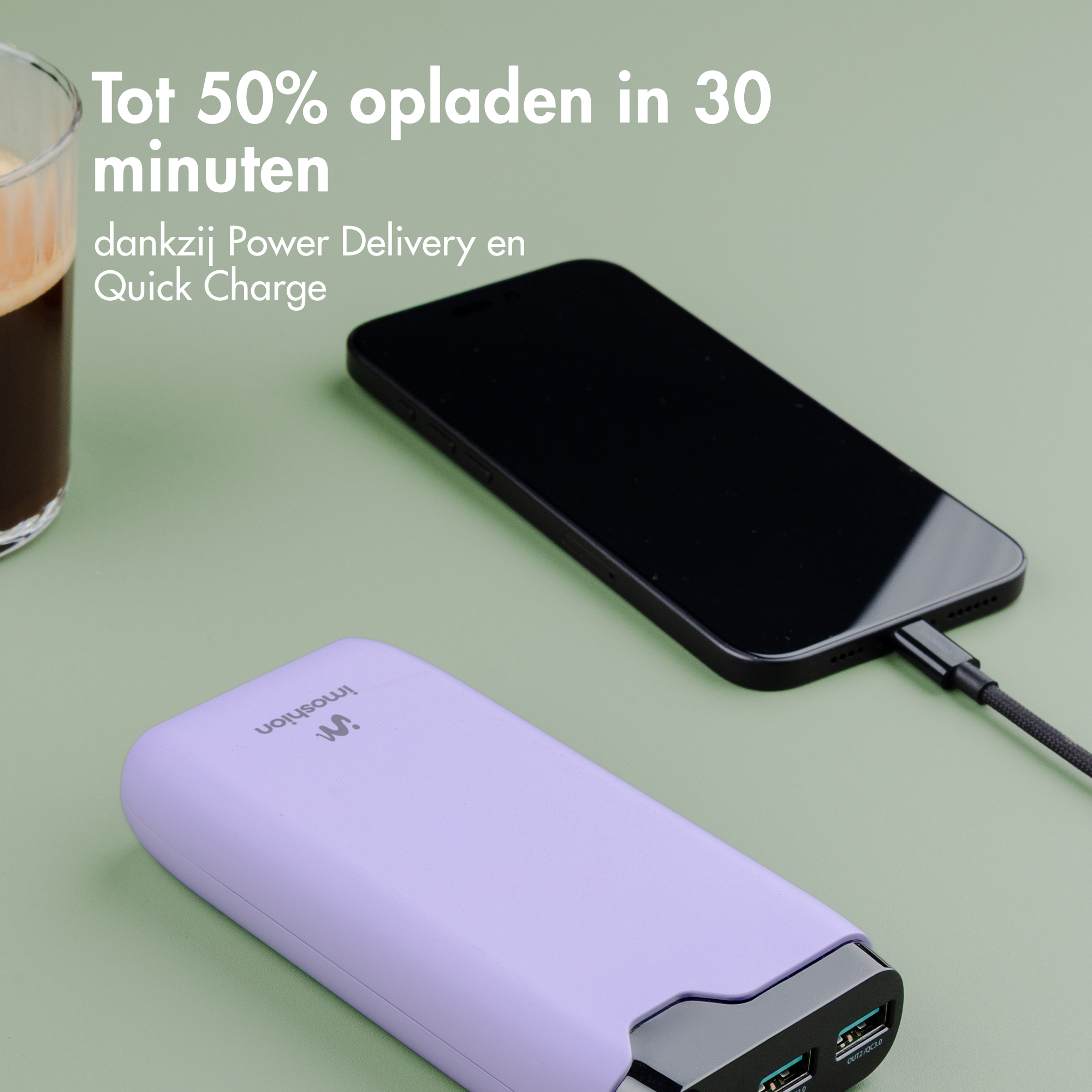 Ein lila Powerbank lädt ein schwarzes Smartphone über ein Kabel, Kaffee daneben.