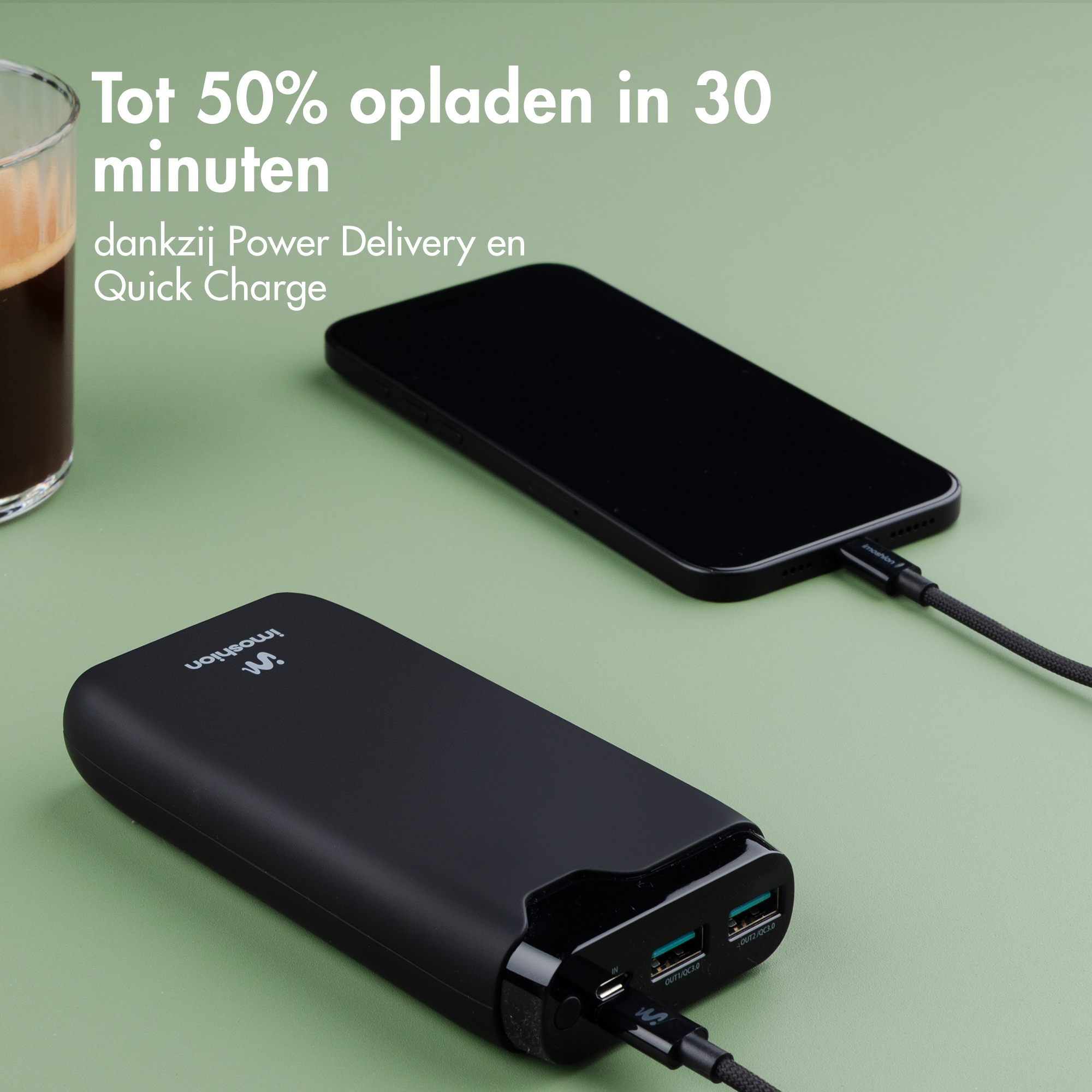 Schwarzes Powerbank lädt ein Smartphone schnell auf. Kaffee daneben.