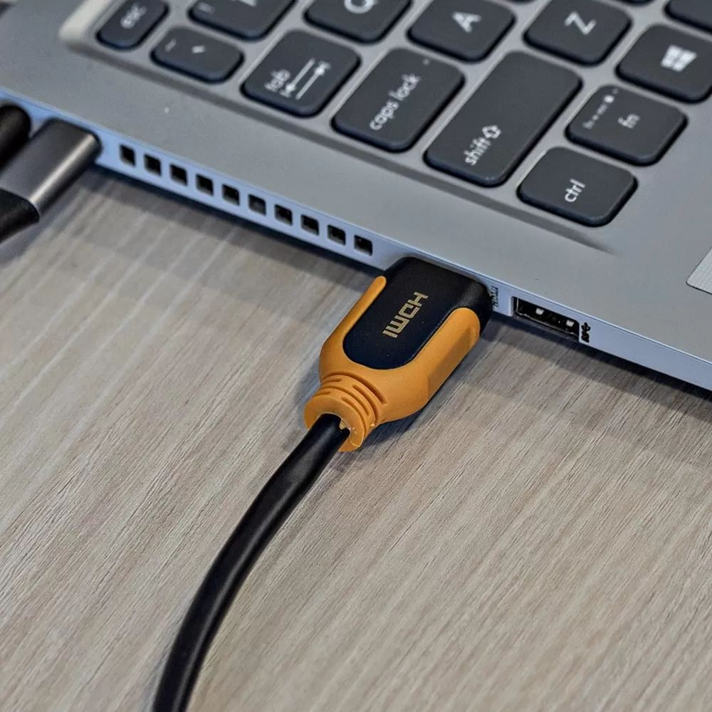 Czarny kabel HDMI z pomarańczowym złączem jest podłączony do laptopa.