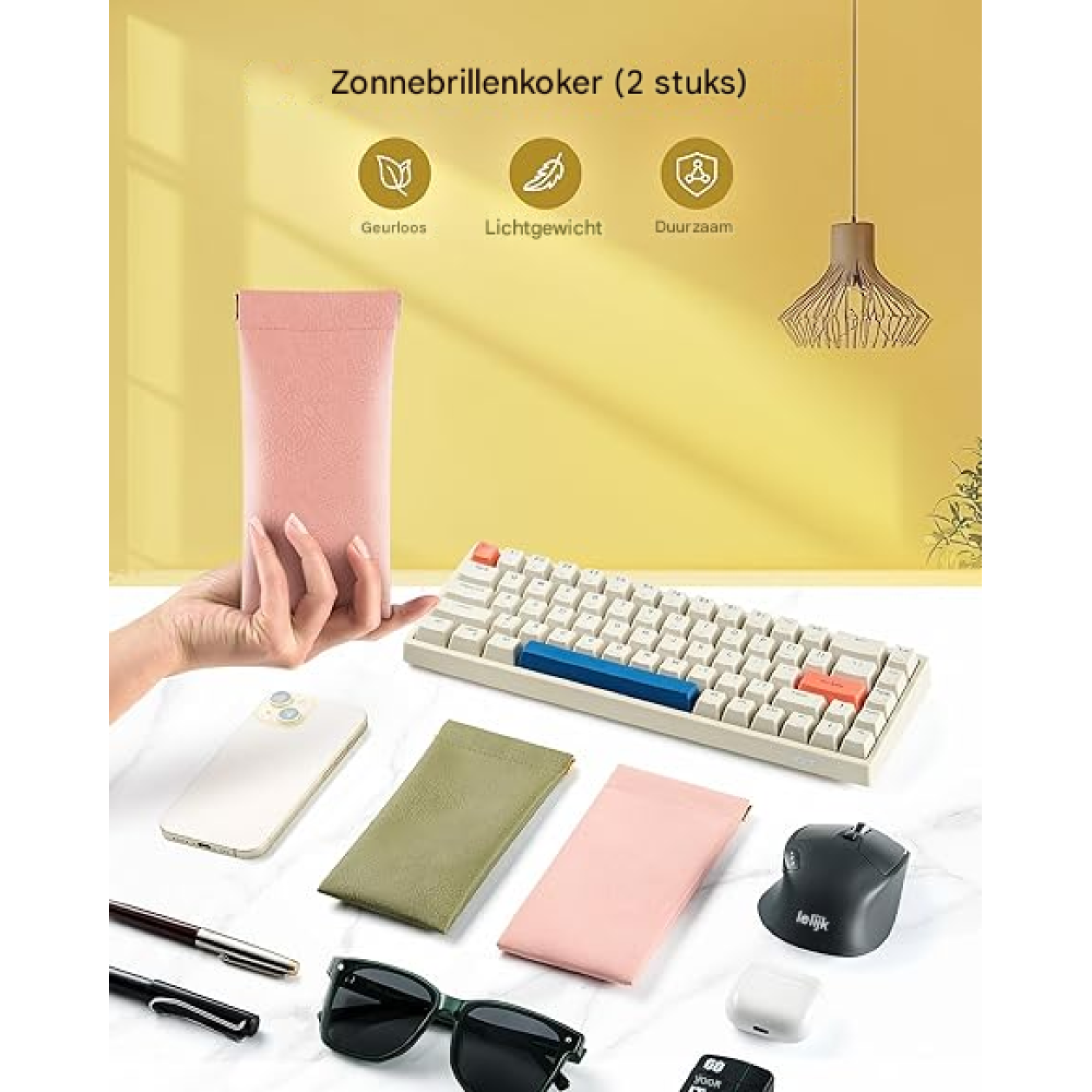 Eine Hand hält eine rosafarbene Brillenetui. Daneben liegen ein Handy, Tastatur, Maus und Brille.