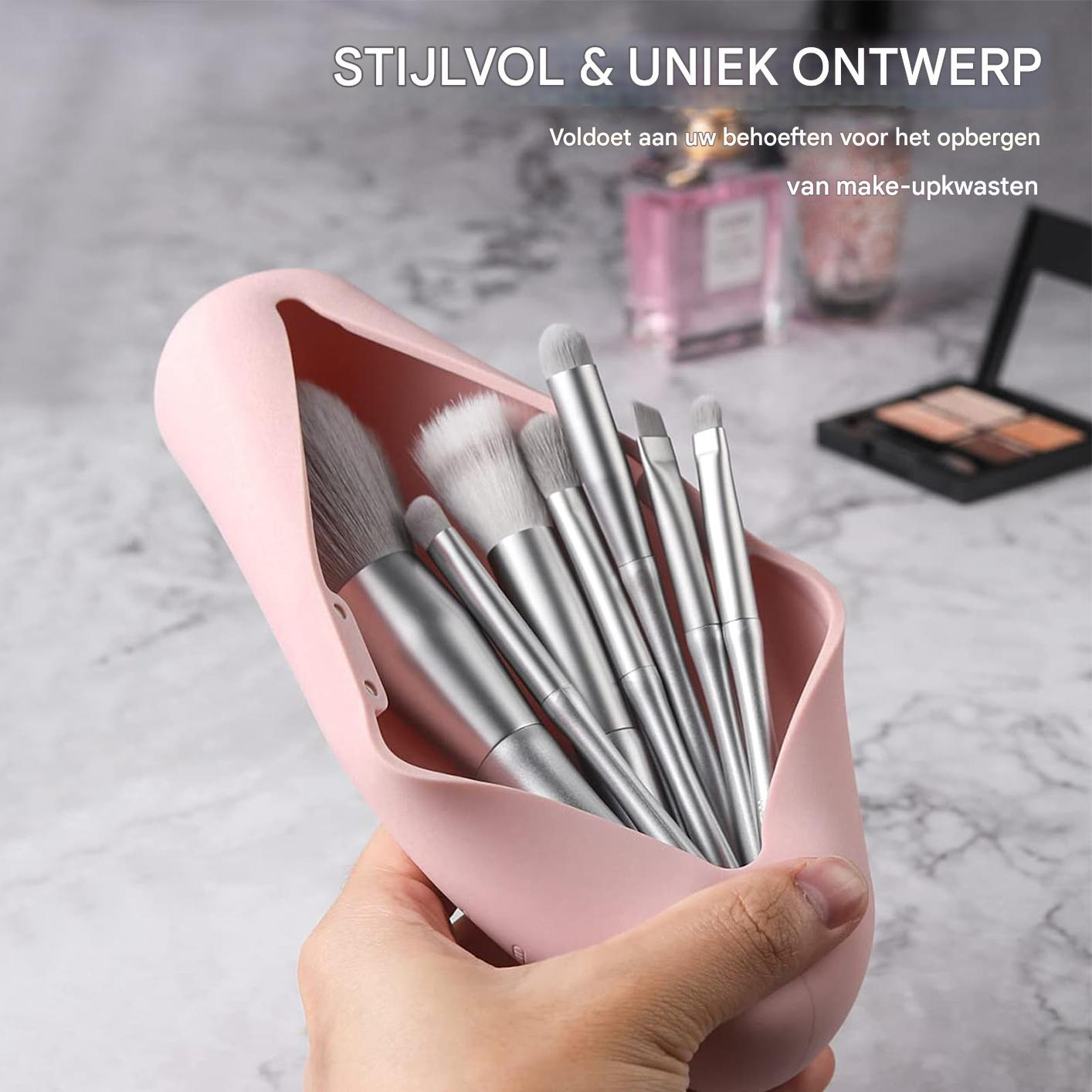 Eine Hand hält einen rosa Behälter mit silbernen Make-up-Pinseln.