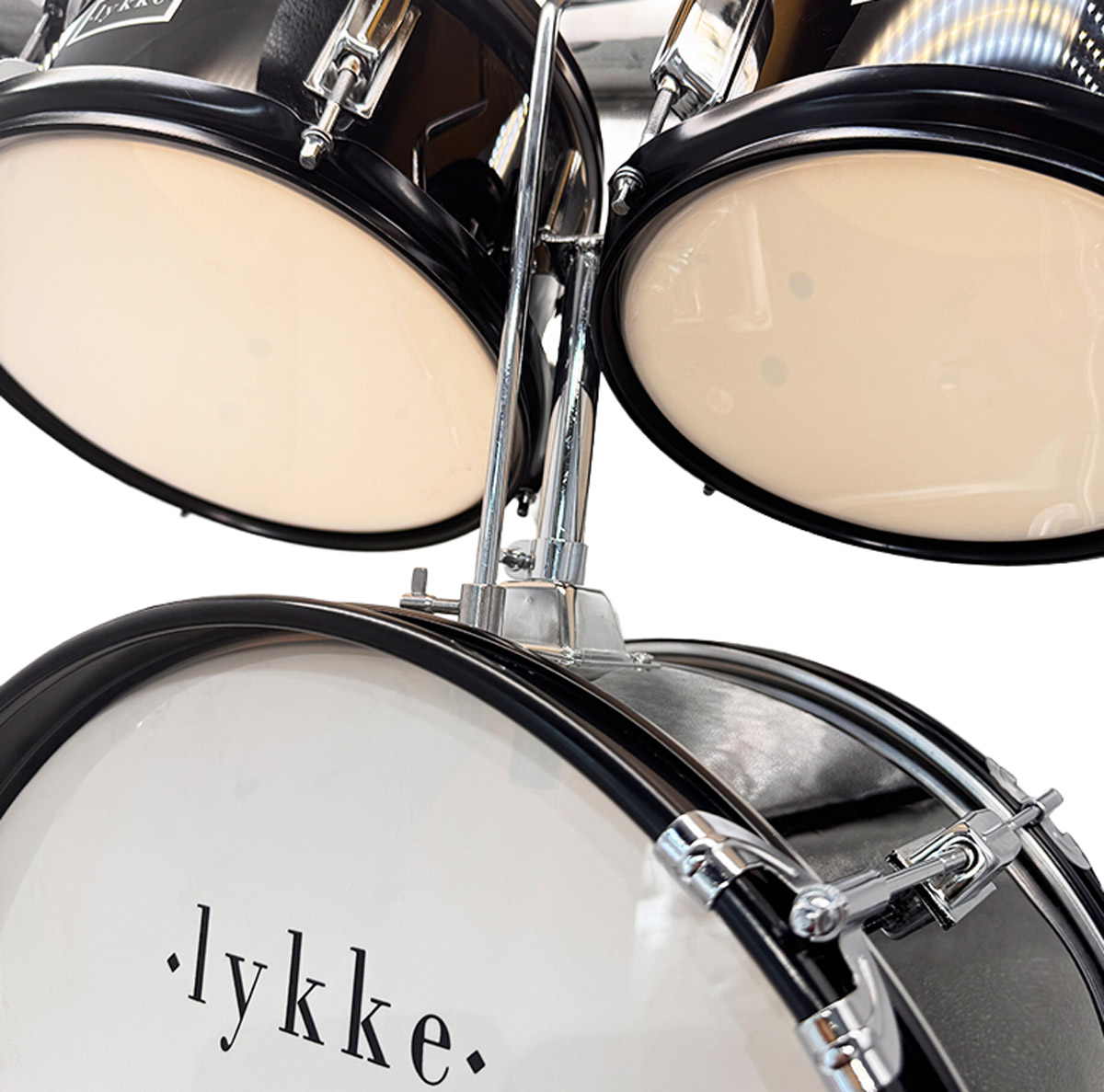 Nahaufnahme eines Schlagzeugs mit schwarzen Trommelkesseln und hellen Fellen. 'lykke' ist auf dem Bassdrumfell.