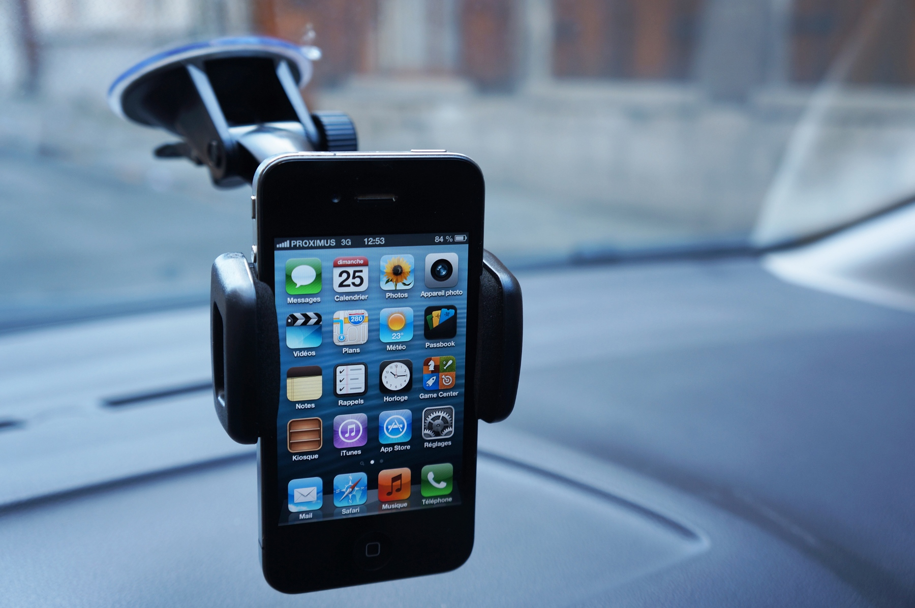 Un iPhone in un supporto per auto mostra la schermata principale con le app.