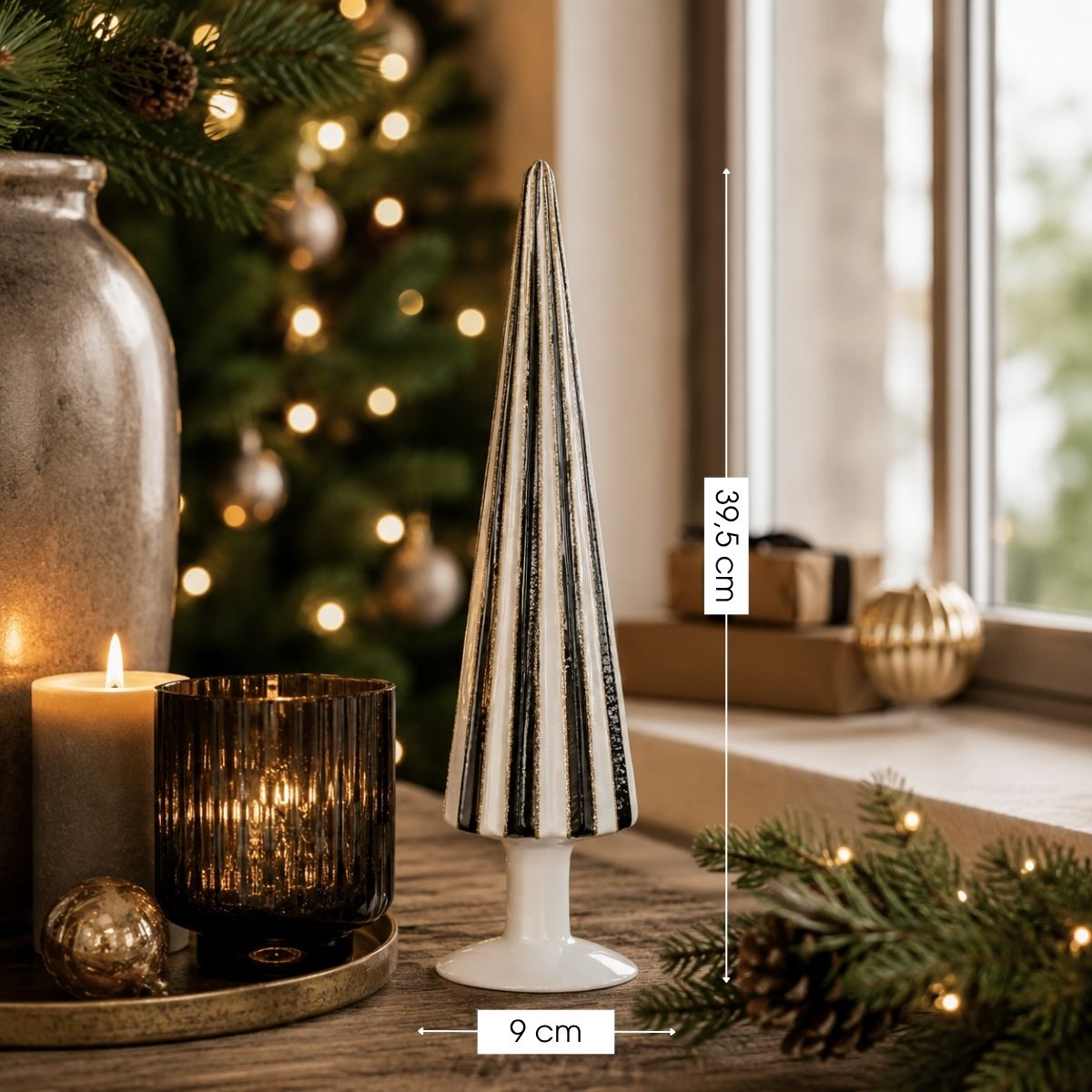 A striped glass tree stand sits beside candles and a vase in front of a Christmas tree.