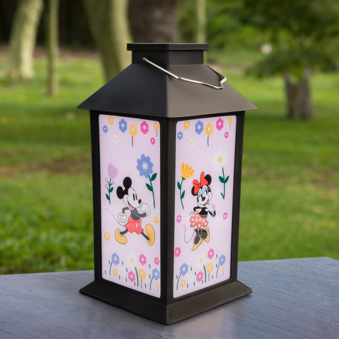 Czarna latarnia z Myszką Mickey i Minnie na różowym, kwiecistym tle.