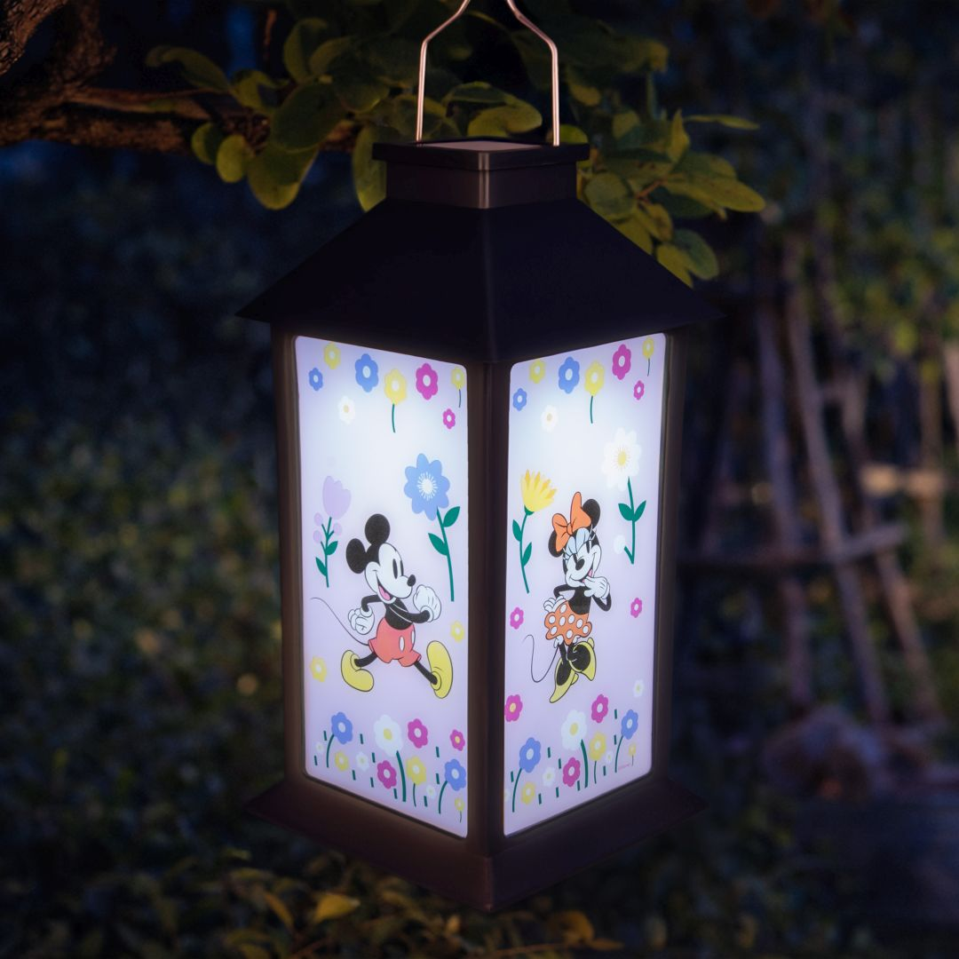 Latarnia z Myszką Miki i Minnie Mouse otoczona kolorowymi kwiatami wisi na zewnątrz.