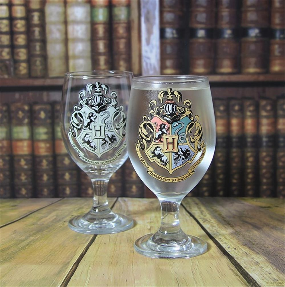 Zwei Gläser mit Hogwarts-Wappen vor einem Bücherregal.
