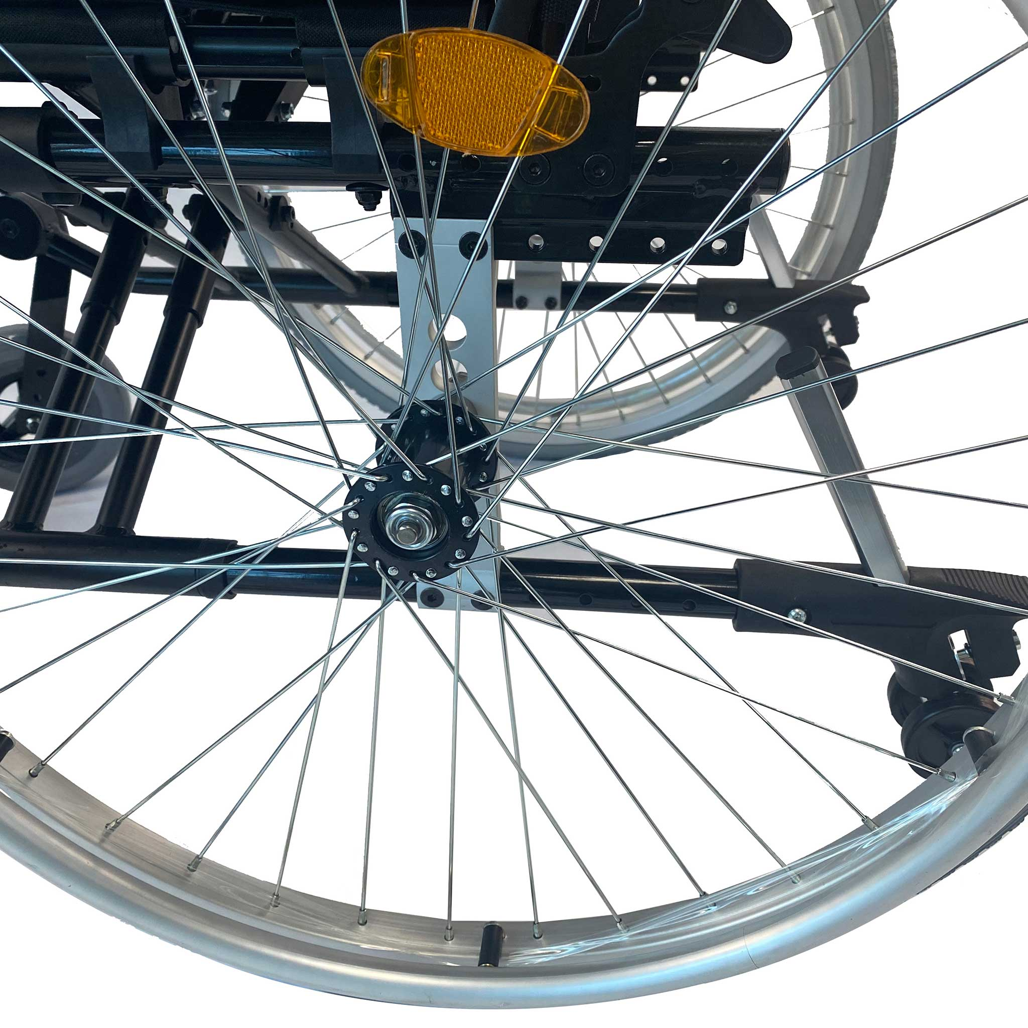 Nahaufnahme eines Rollstuhls mit Fokus auf Speichen, Felge und reflektierendem Element.
