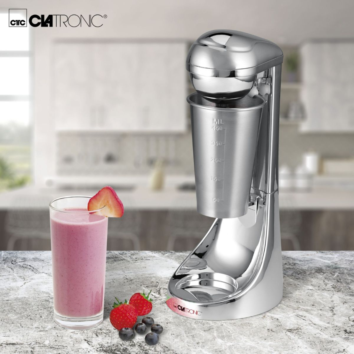 Ein silberner Milchshake-Mixer mit Glas und Früchten auf einem Marmortisch.