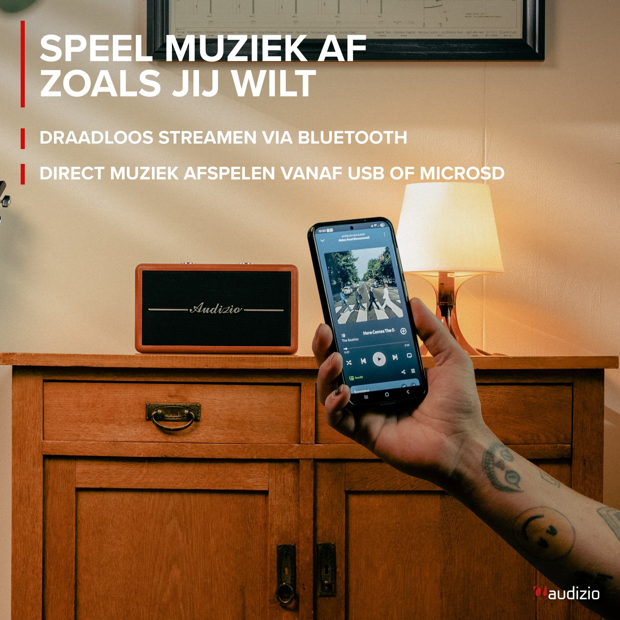 Un smartphone muestra música, junto a un altavoz marrón en un mueble de madera.