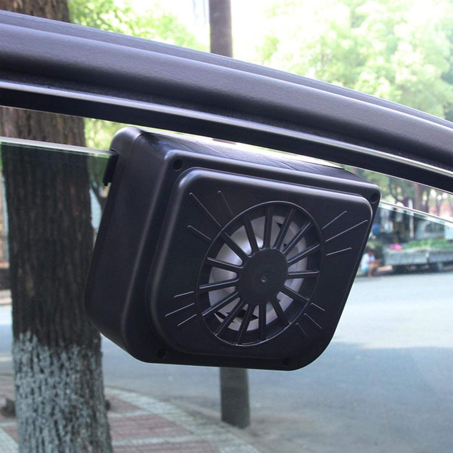 Ein schwarzer Lüfter mit Solarpanel, der am Fenster eines Autos befestigt ist.