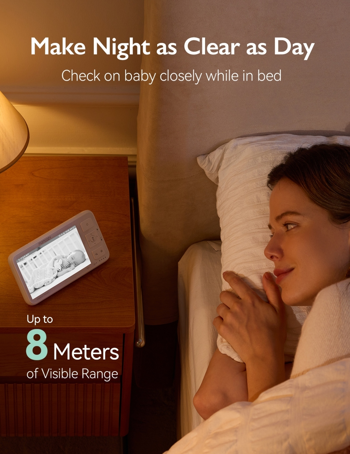 Una donna è a letto, guarda lo schermo di un baby monitor che mostra un bambino addormentato.