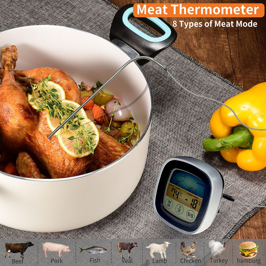 Ein gebratenes Hähnchen mit Zitrone und Kräutern in einem Topf, daneben ein Fleischthermometer.
