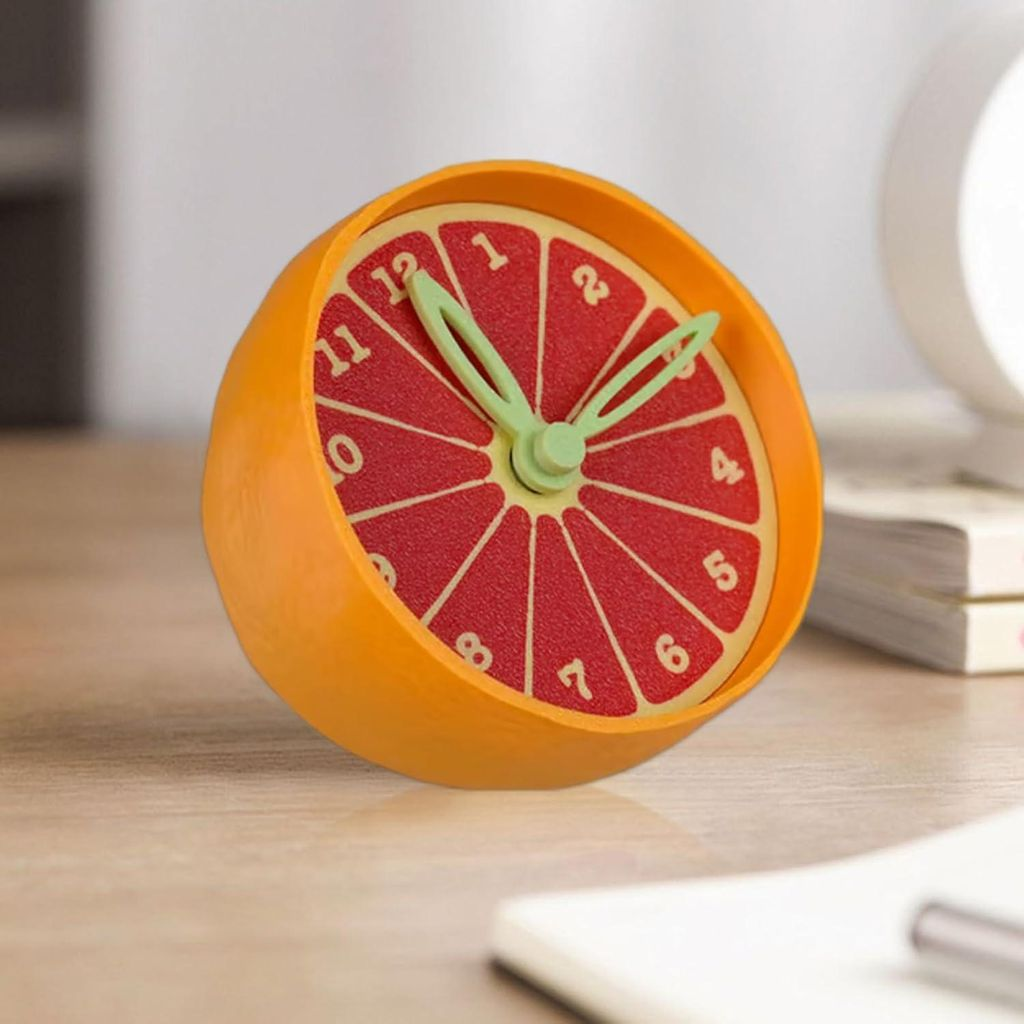 Ein orangefarbener Wecker in Form einer Grapefruit-Scheibe mit grünen Zeigern.