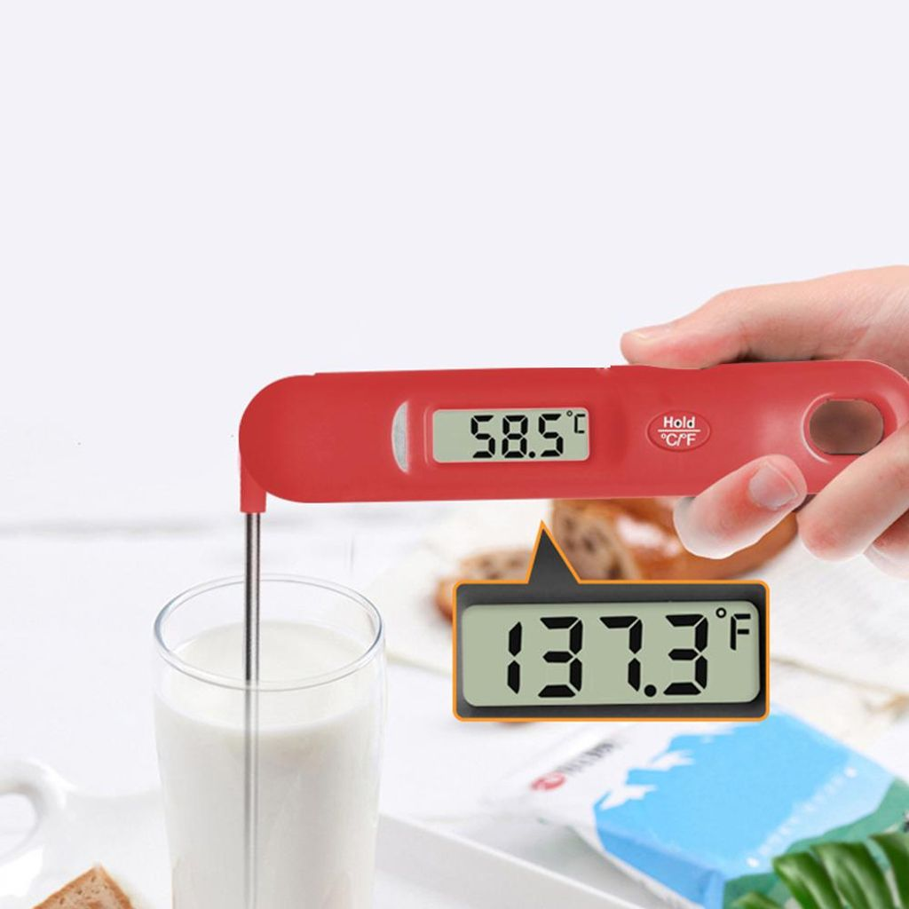 Ein rotes Digitalthermometer misst die Temperatur von Milch in einem Glas.