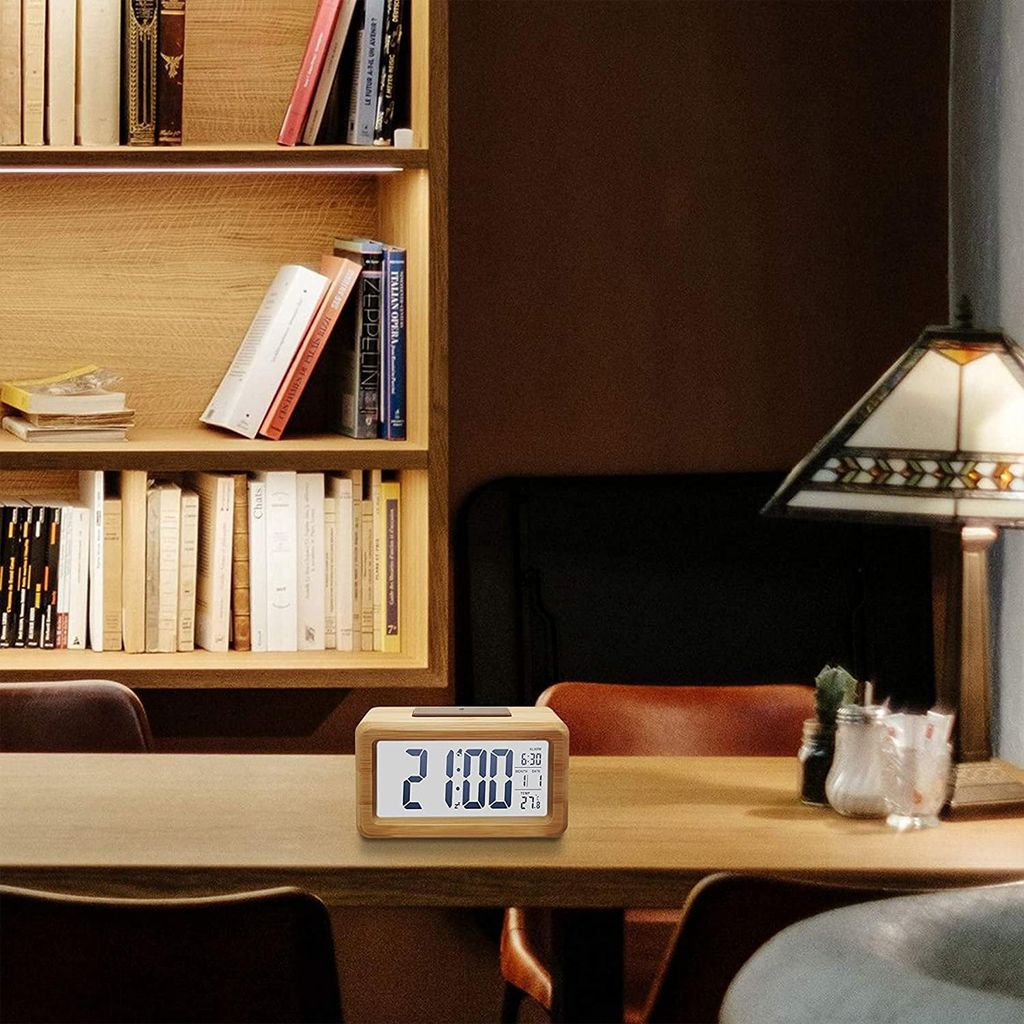 Ein Holzweckeruhr zeigt 21:00. Bücherregal im Hintergrund.
