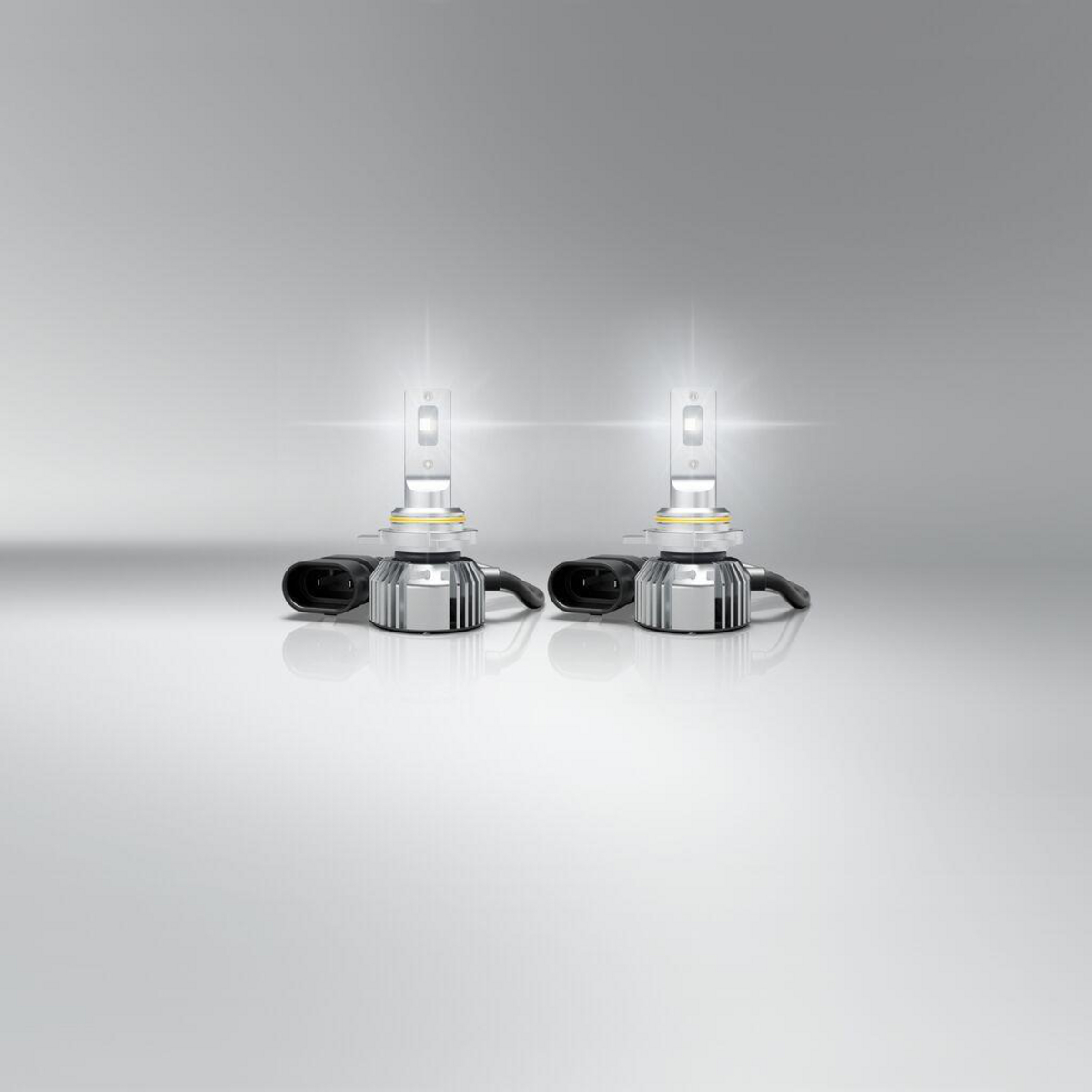 Zwei weiße LED-Autoscheinwerfer mit silbernen Sockeln und schwarzen Kabeln.