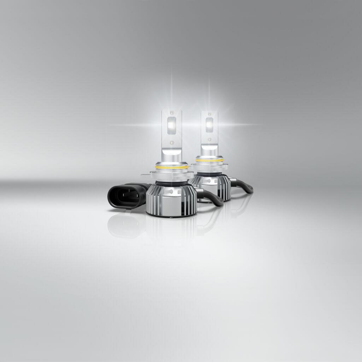 Zwei leuchtende LED-Autolampen mit silbernen Kühlkörpern und schwarzen Kabeln.