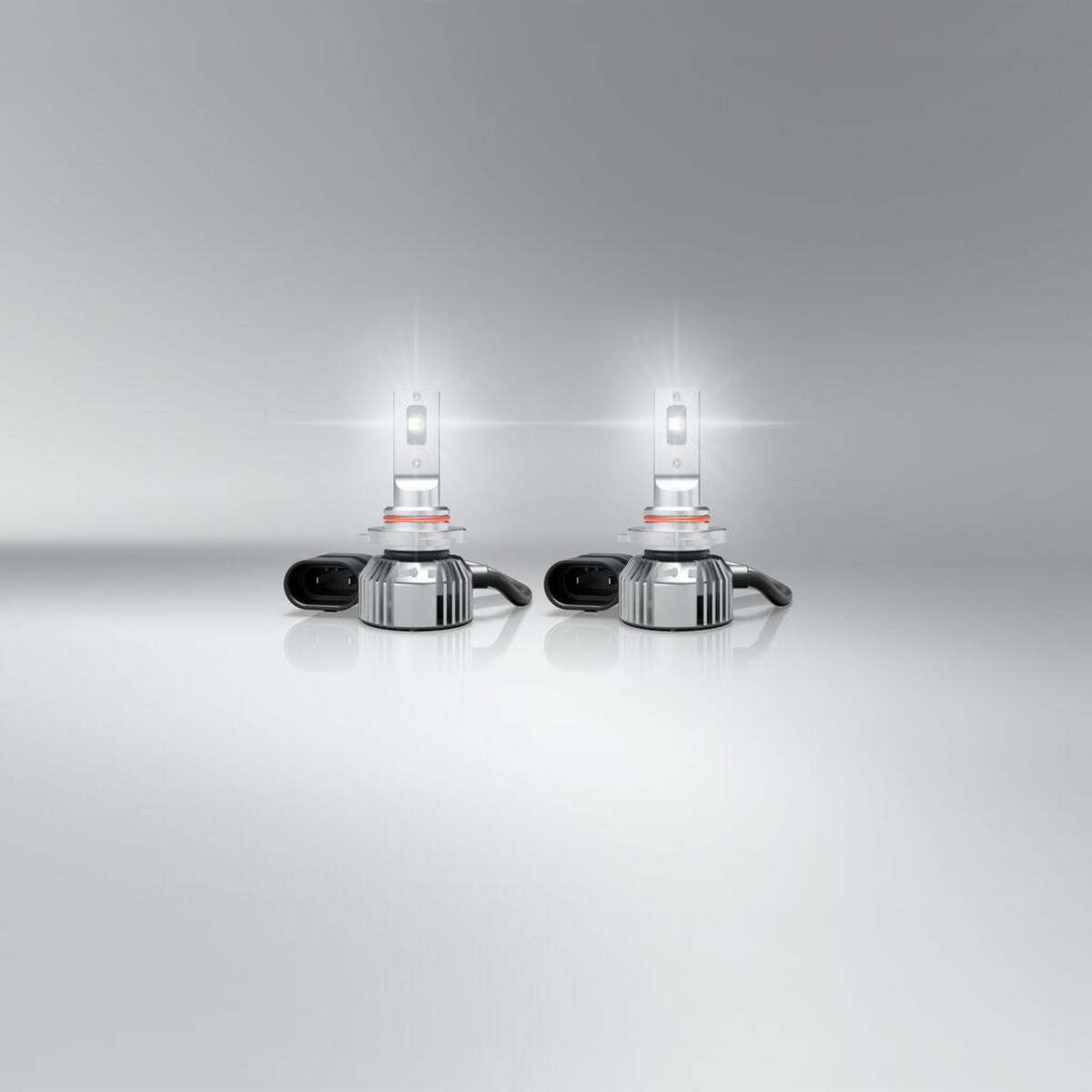 Zwei weiße LED-Autoscheinwerfer mit silbernen Kühlkörpern und schwarzen Steckern.