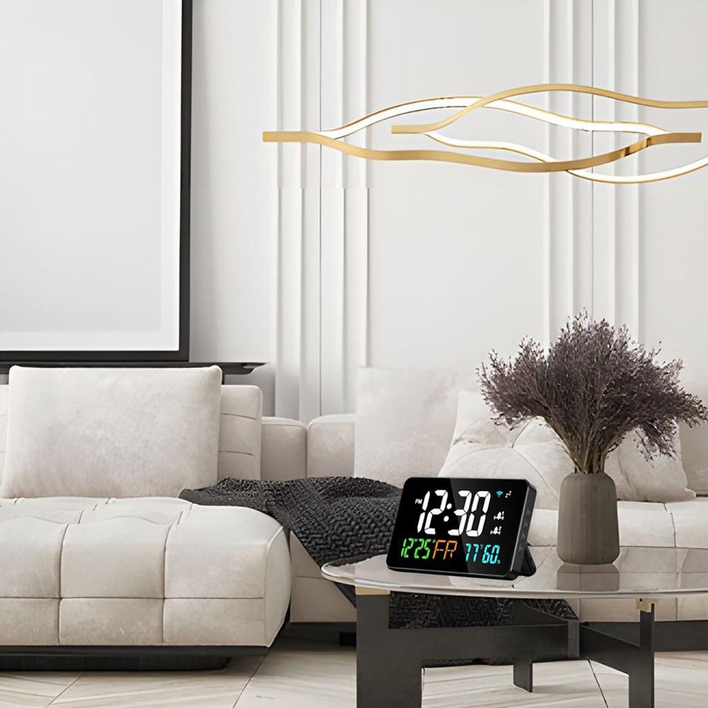 Ein digitaler Wecker mit Datum und Temperatur steht auf einem Glastisch in einem modernen Wohnzimmer.