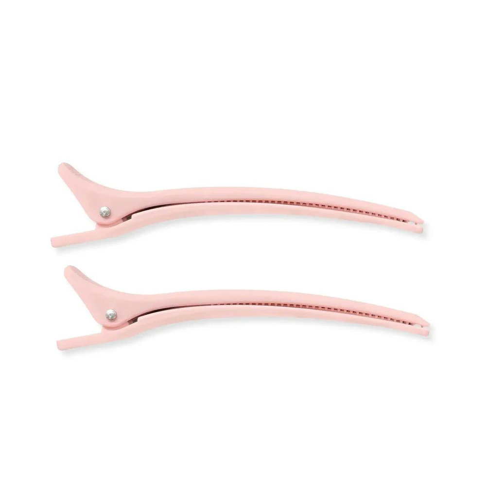 Deux pinces à cheveux rose pâle sont allongées côte à côte sur fond blanc.