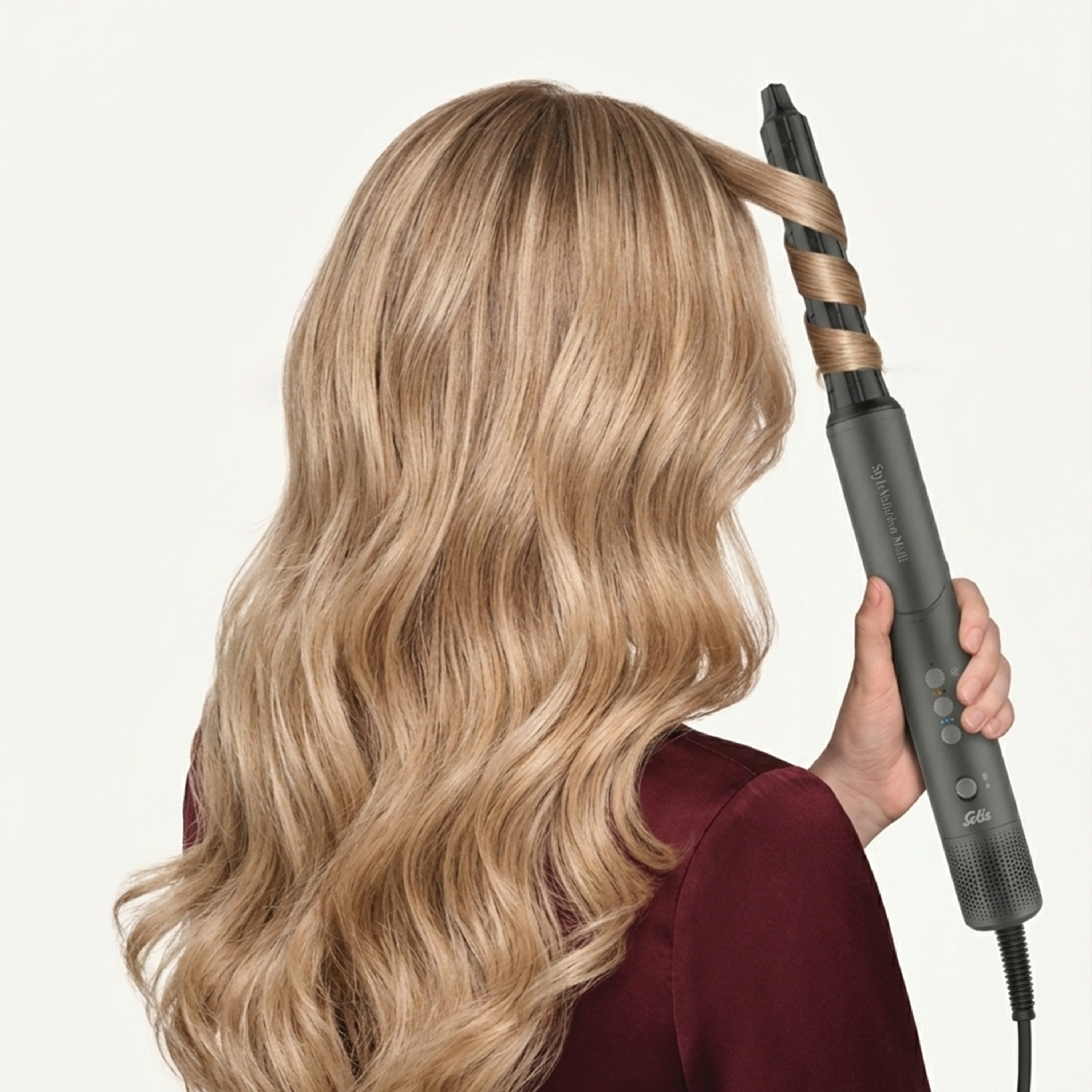 Una donna con capelli biondi usa un arricciacapelli per acconciarli.