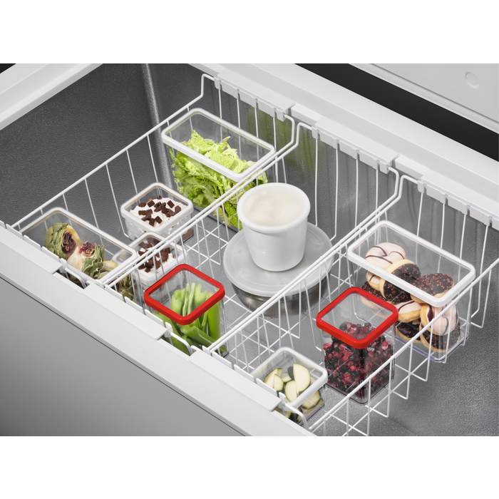 Congelatore con cestini contenenti alimenti come verdure, ciambelle e bacche.