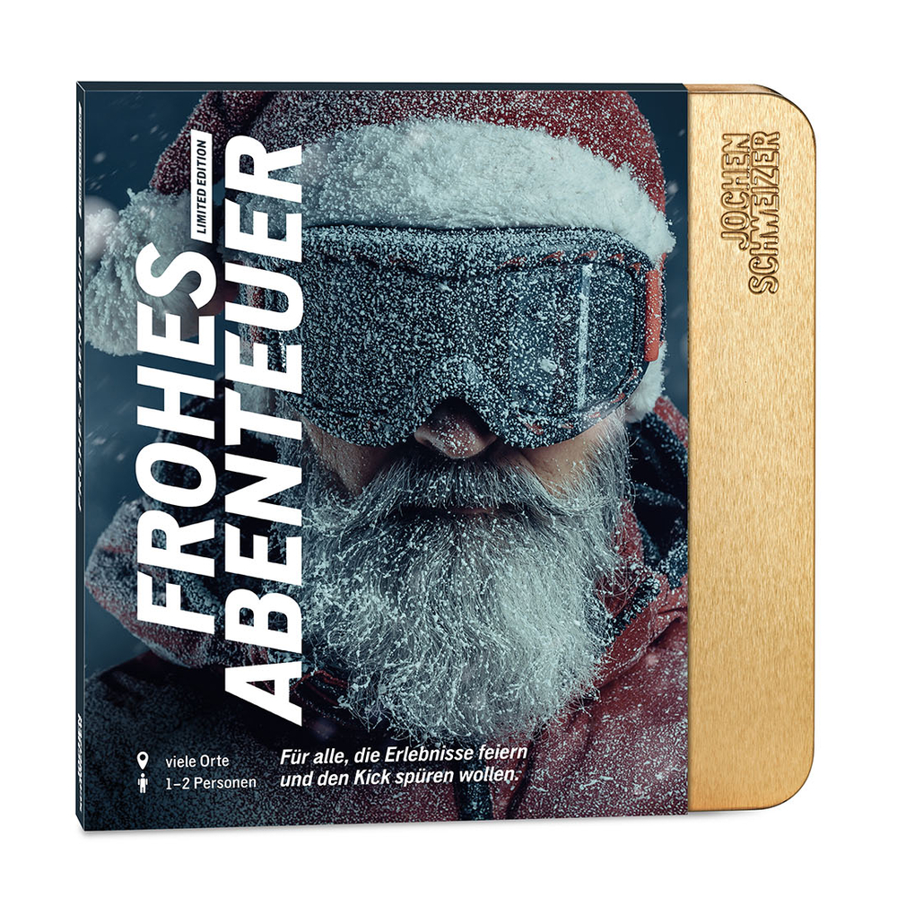 Ein Mann mit Weihnachtsmannmütze und Skibrille, bedeckt mit Schnee.