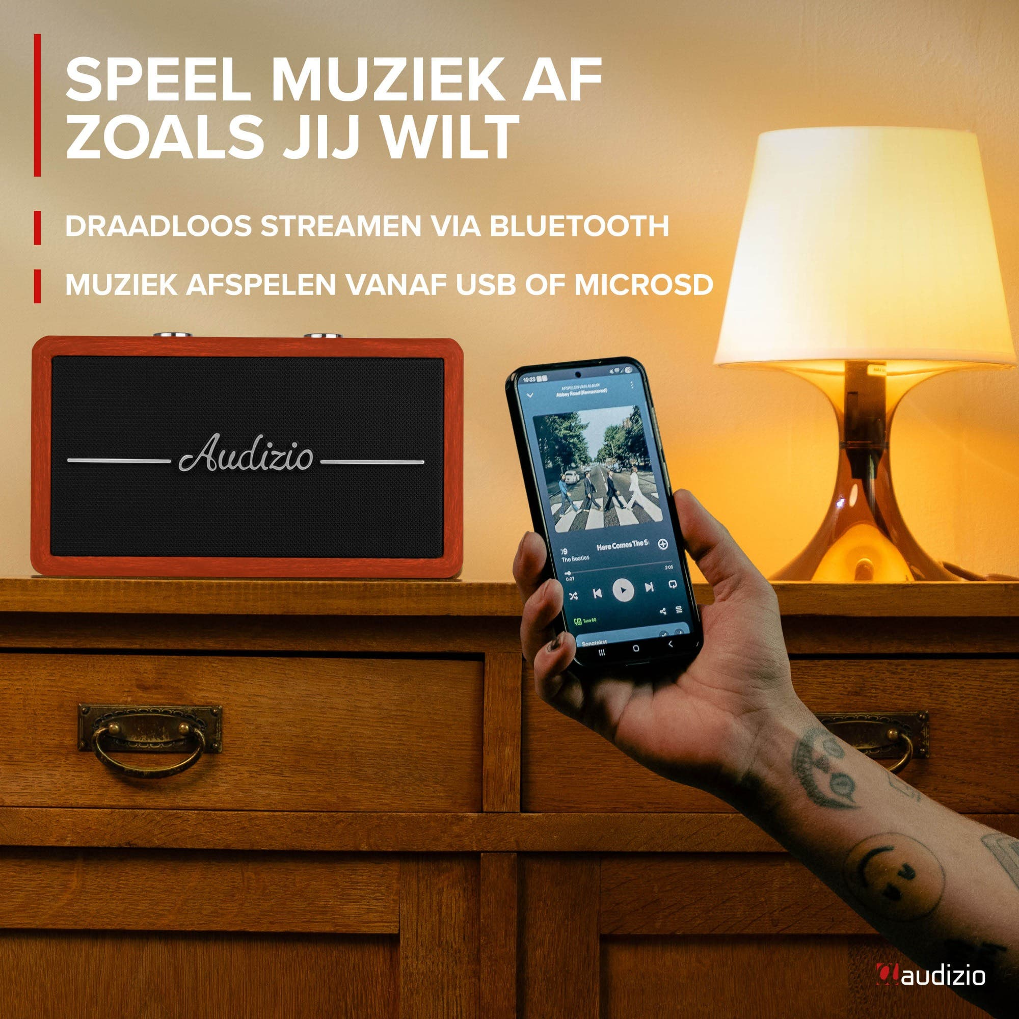 Un altavoz y un smartphone reproduciendo música. Una mesita de noche de madera.