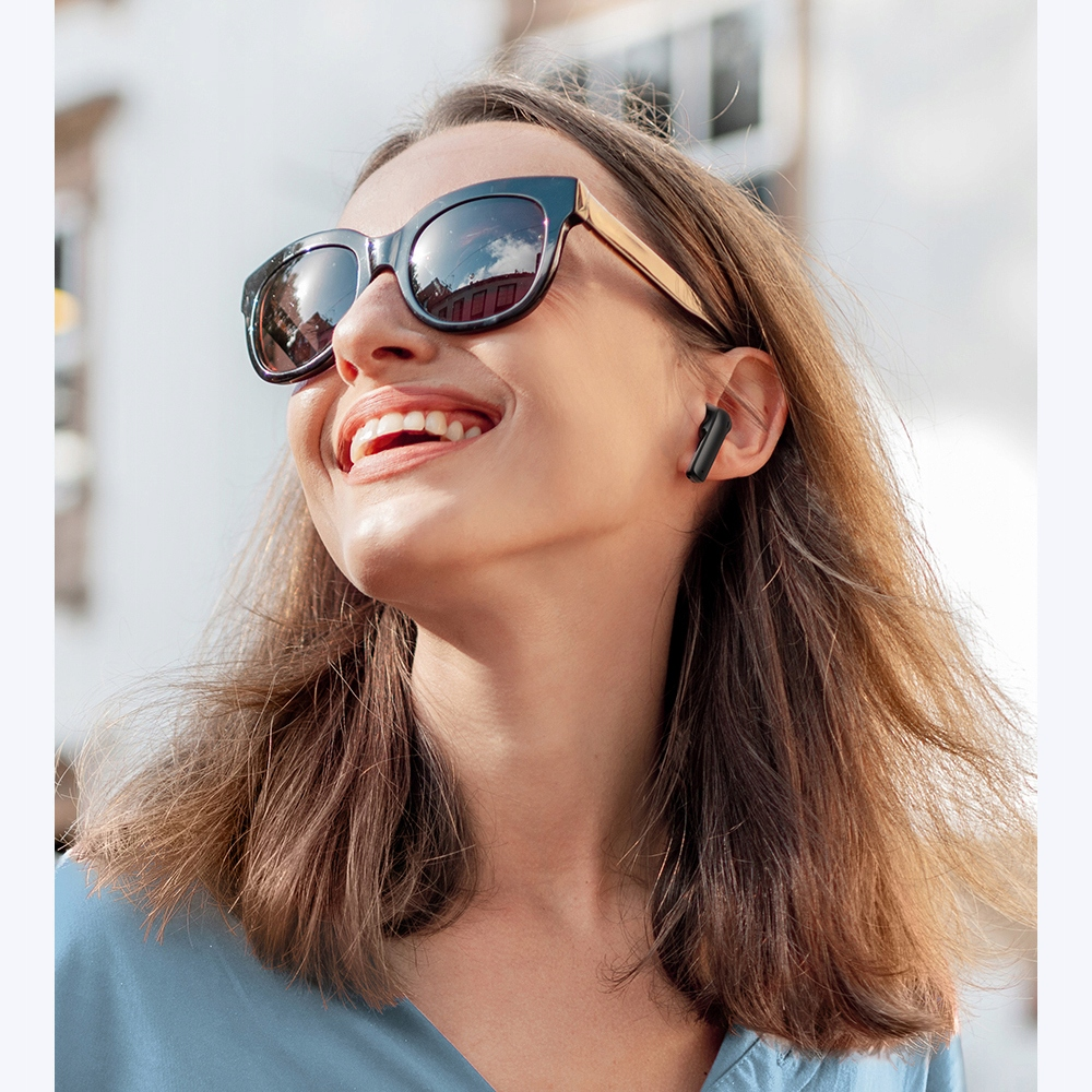 Frau mit Sonnenbrille und Ohrhörern lächelt nach oben