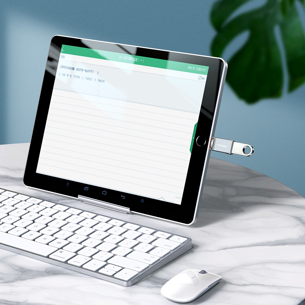 Ein Tablet mit Tastatur und Maus auf einem Marmortisch, ein USB-Stick steckt im Tablet.