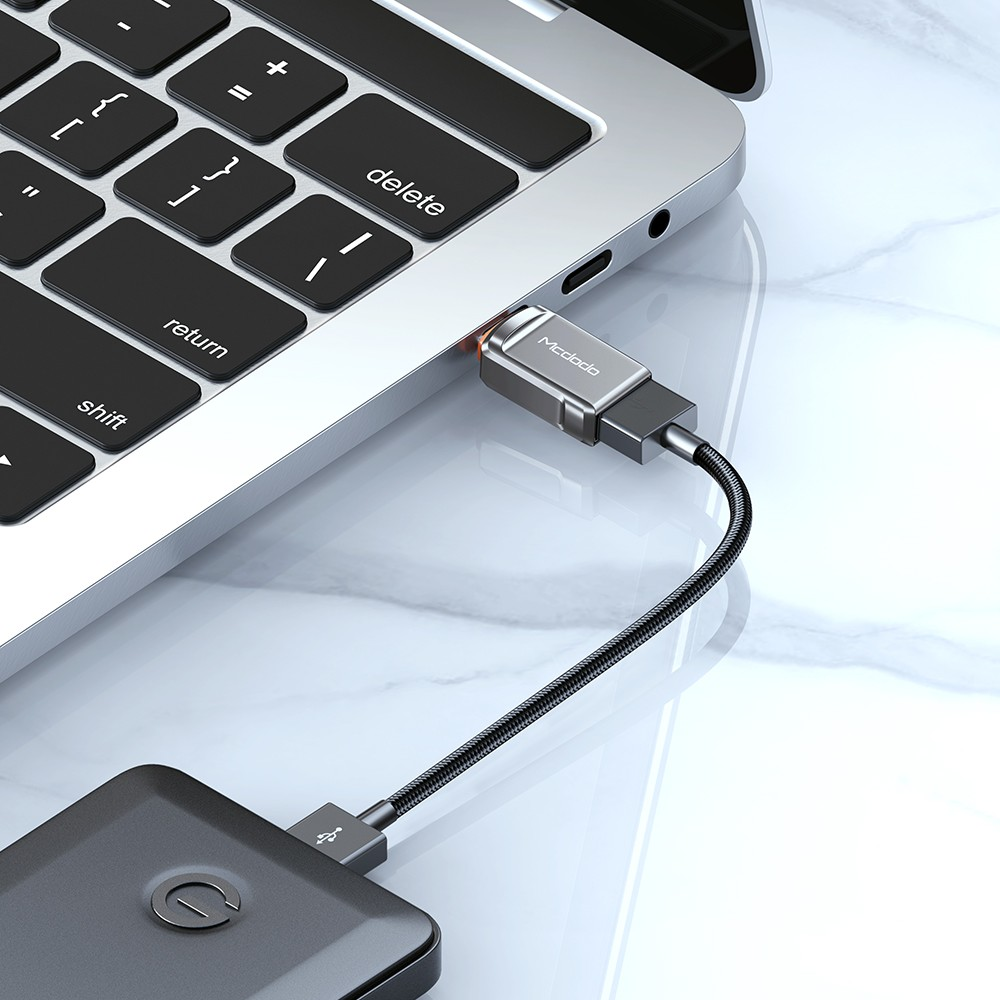 Ein Ladekabel verbindet ein graues Netzteil mit einem Laptop.