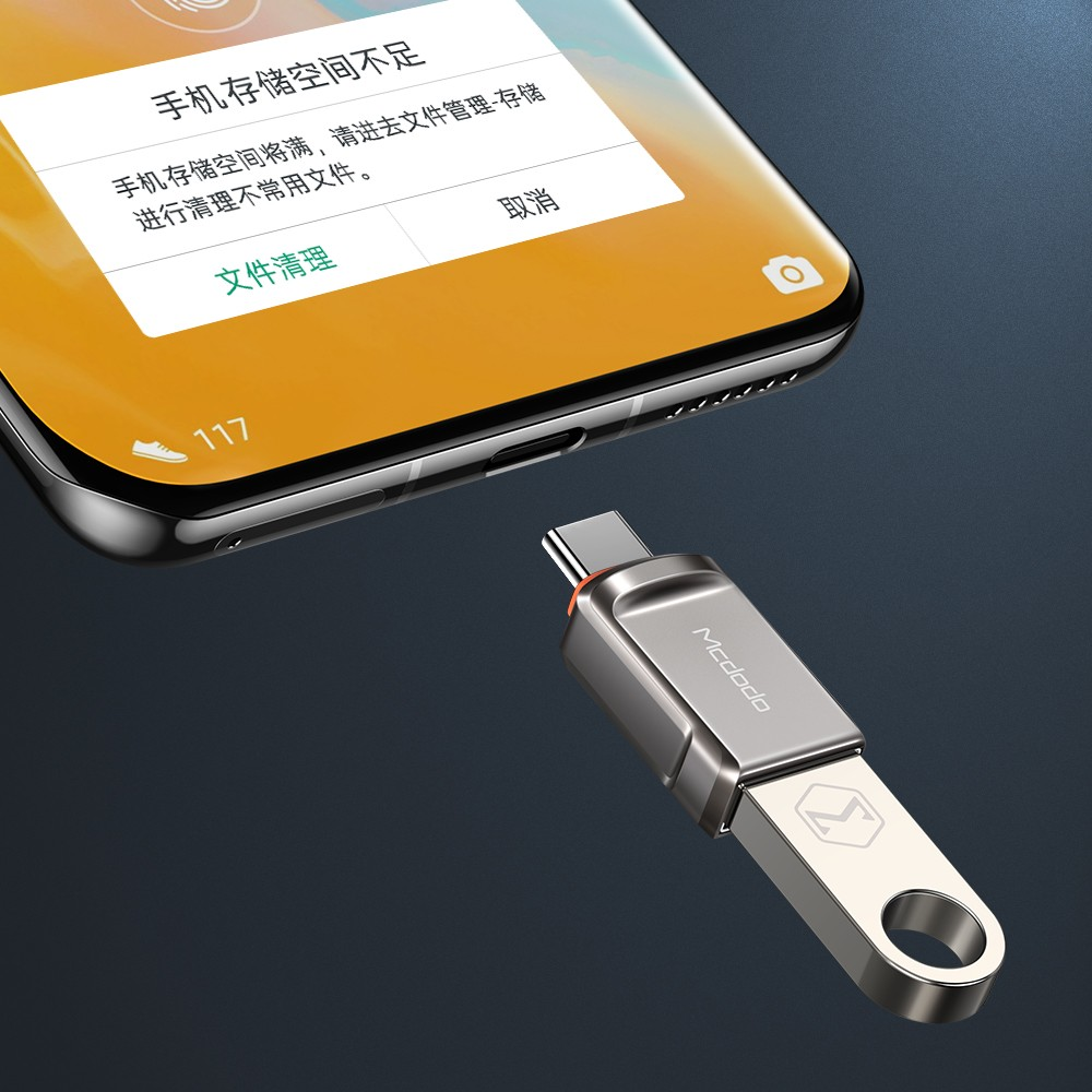 Ein silberner USB-Stick mit Typ-C-Anschluss liegt neben einem Smartphone, das eine Speichermeldung anzeigt.