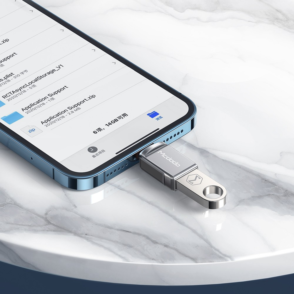 Ein silberner USB-Stick steckt in einem blauen Smartphone, das auf Marmor liegt.