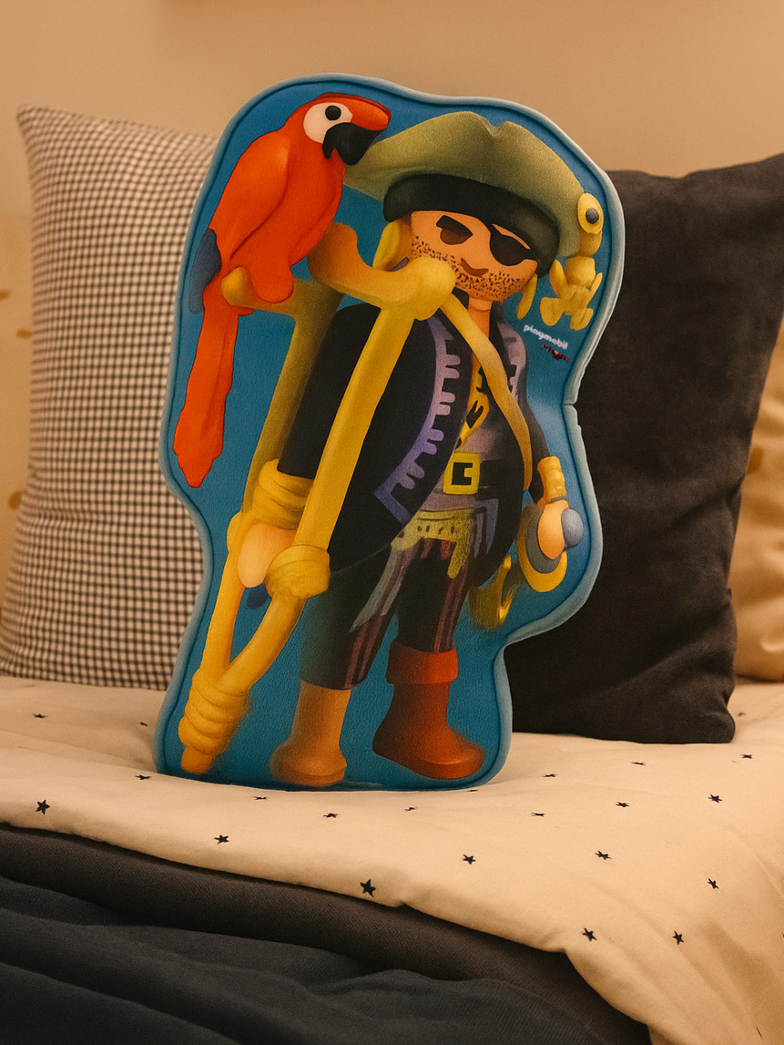 Ein Playmobil-Piratenkissen mit einem Papagei auf der Schulter, das auf einem Bett liegt.