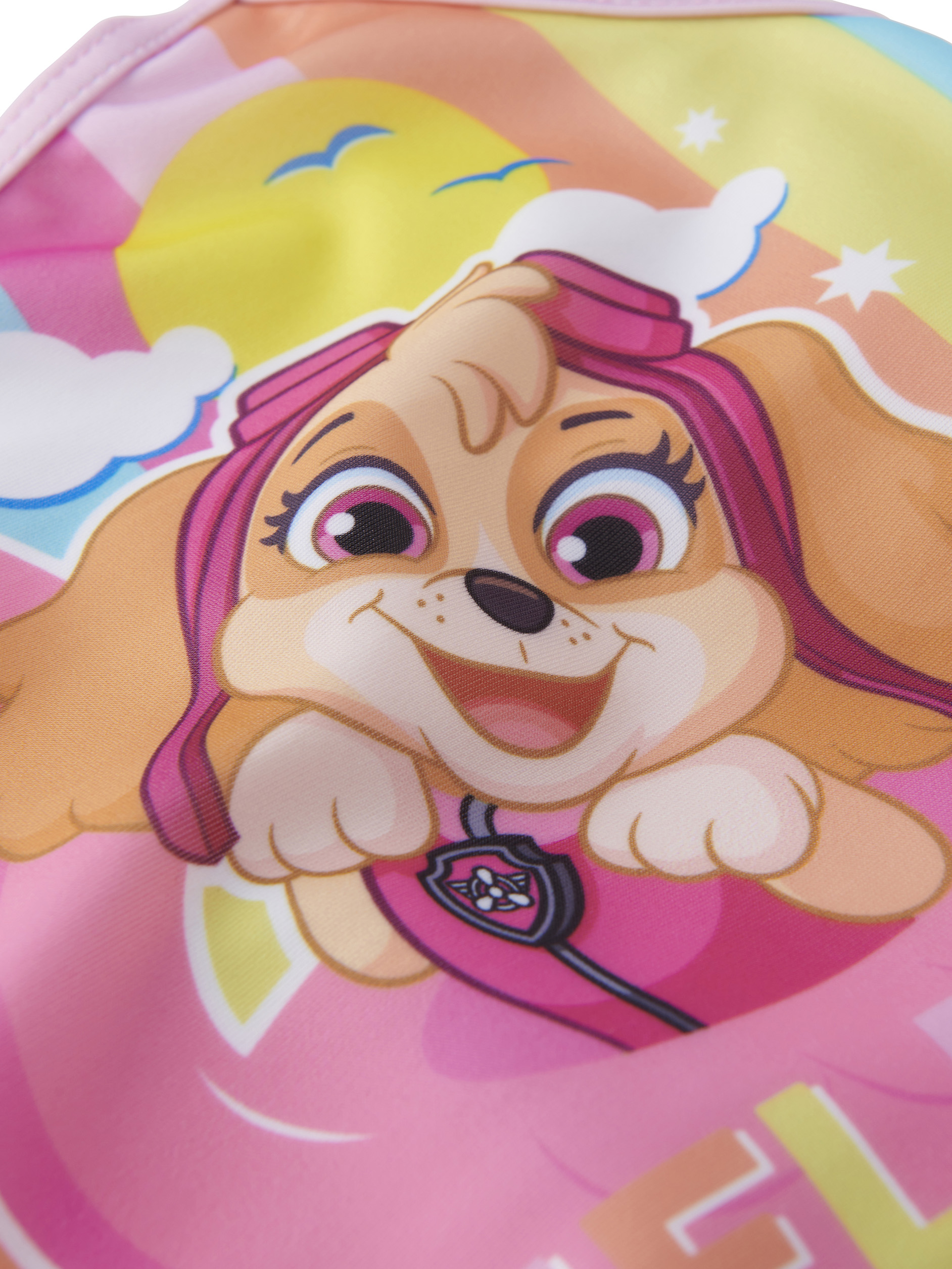 Ein Cartoon-Hund mit pinken Haaren und grossen Augen lacht vor einem bunten Himmel.