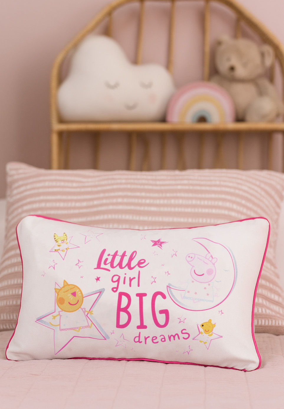 Ein weißes Kissen mit pinkem Rand zeigt Cartoonfiguren und den Text 'Little girl BIG dreams'.