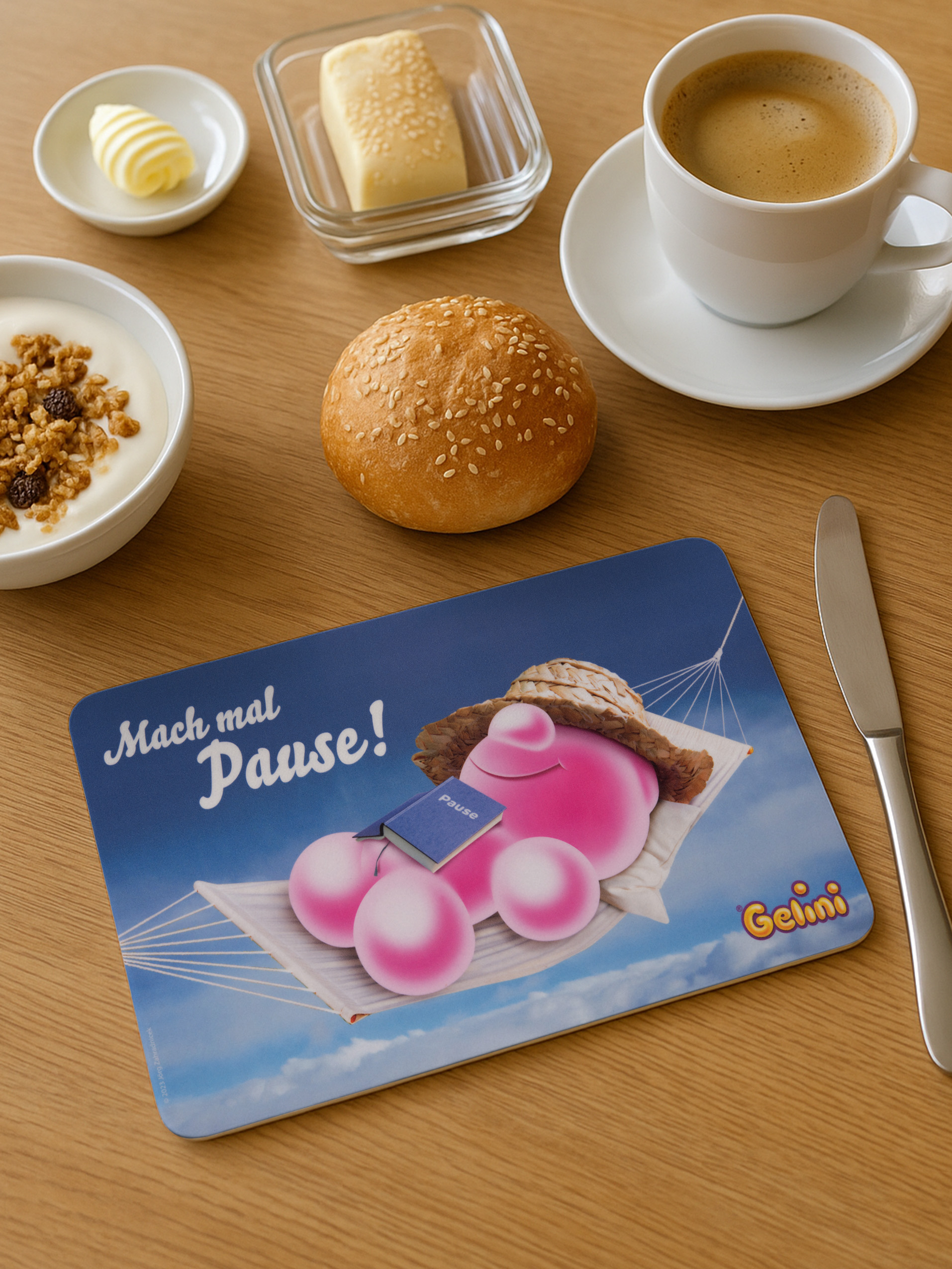 Ein rosa Wesen in Hängematte mit Buch, auf einem Tisch mit Frühstück.